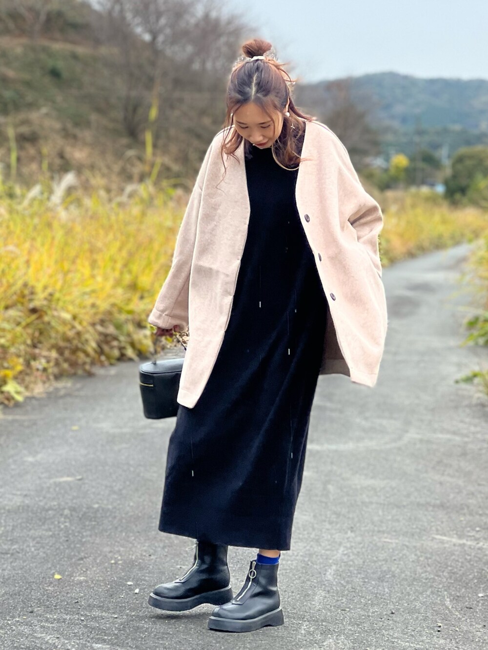 ピンク系のノーカラーコート、ブラック系のワンピース、ブラック系のブーツを着用したレディースの秋コーディネートの3枚目の写真
