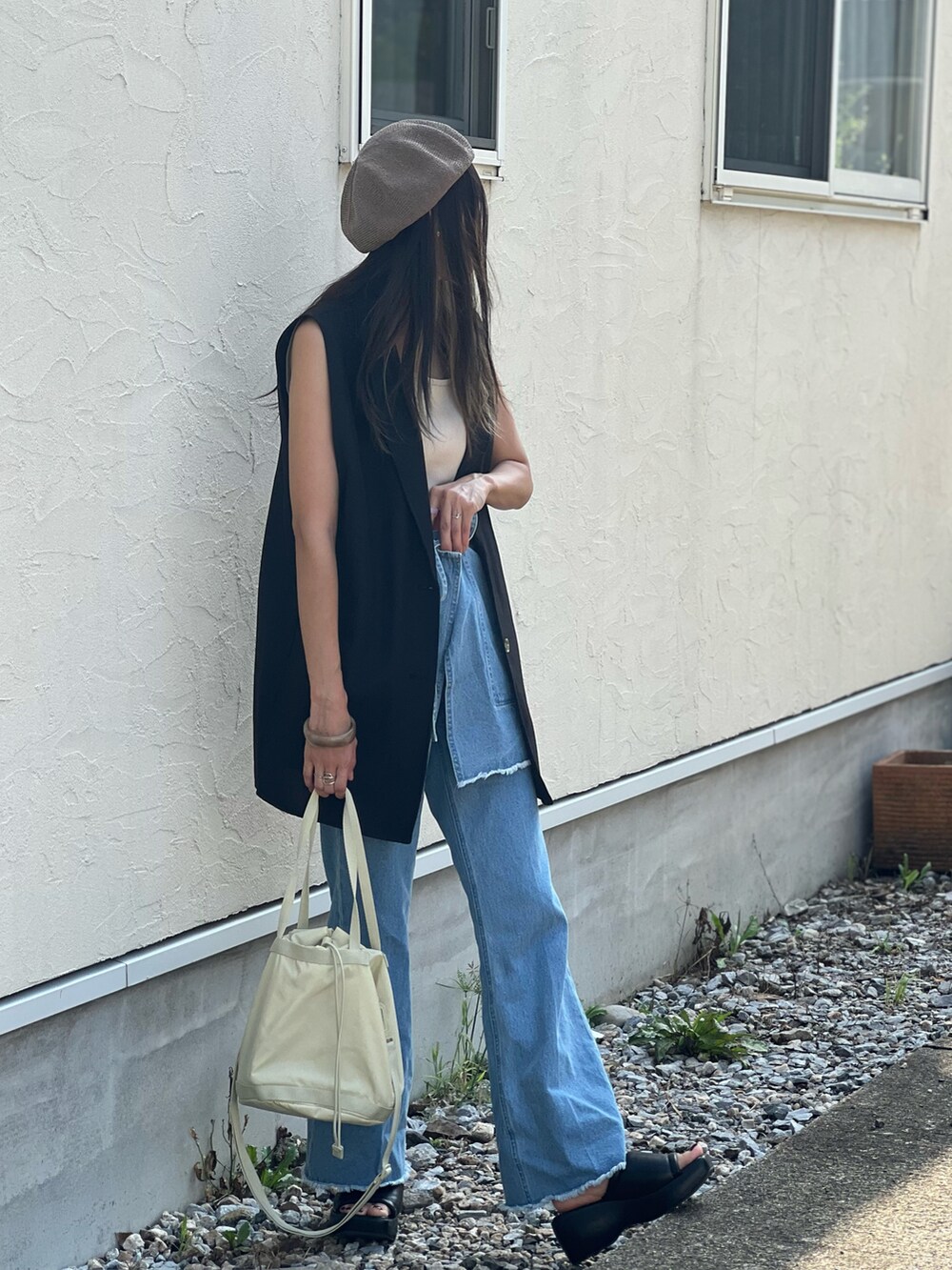 ブルー系のデニムパンツ、ベージュ系のショルダーバッグ、ブラック系のサンダルを着用したレディースの夏コーディネートの5枚目の写真