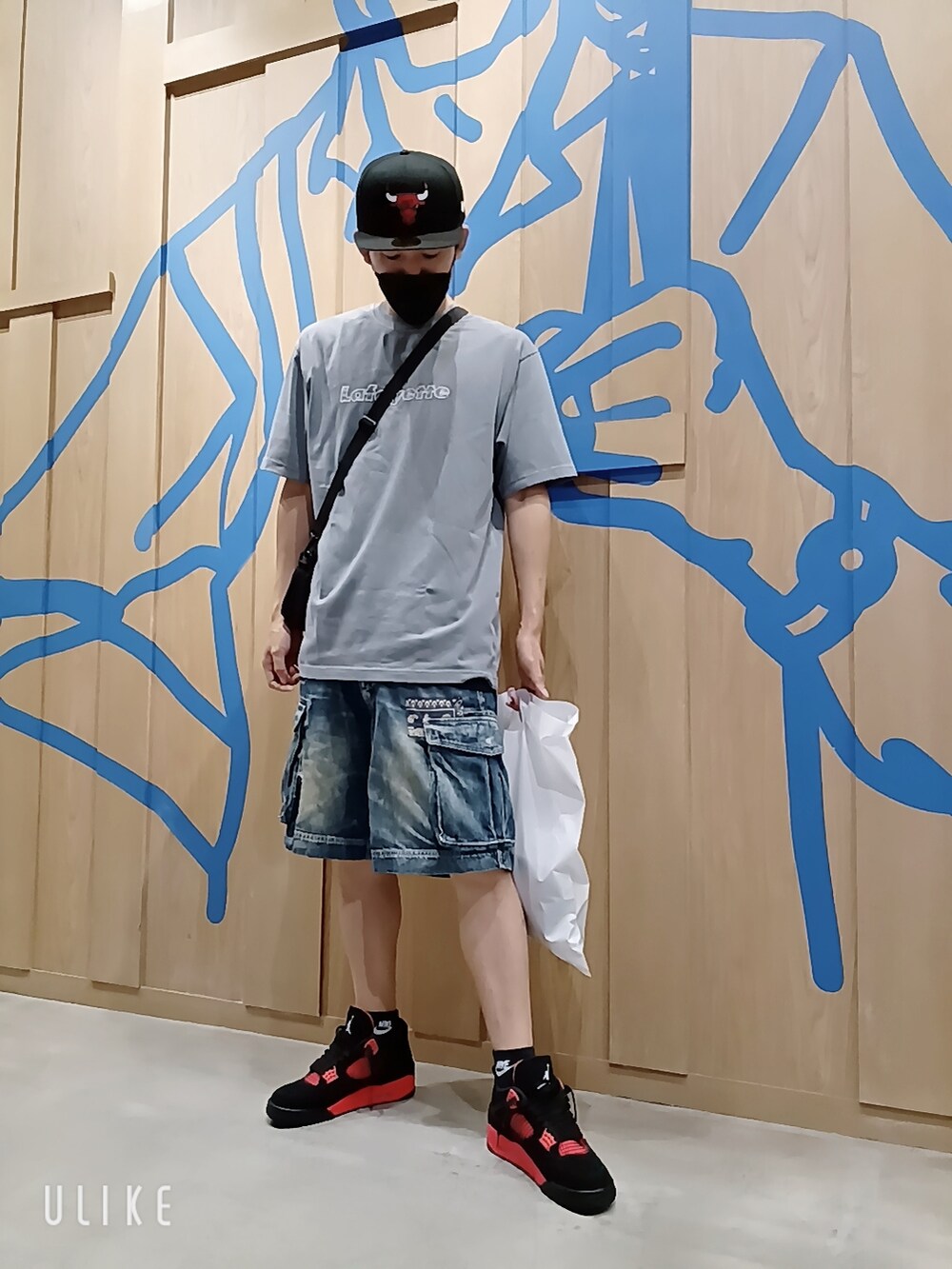 レッド系のスニーカー、グレー系のTシャツ/カットソー、ブラック系のキャップを着用したメンズの秋コーディネートの4枚目の写真