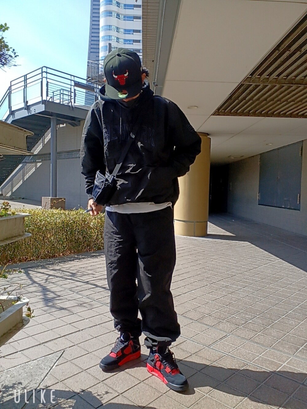 レッド系のスニーカー、ブラック系のカーゴパンツ、ブラック系のパーカーを着用したメンズの春コーディネートの2枚目の写真