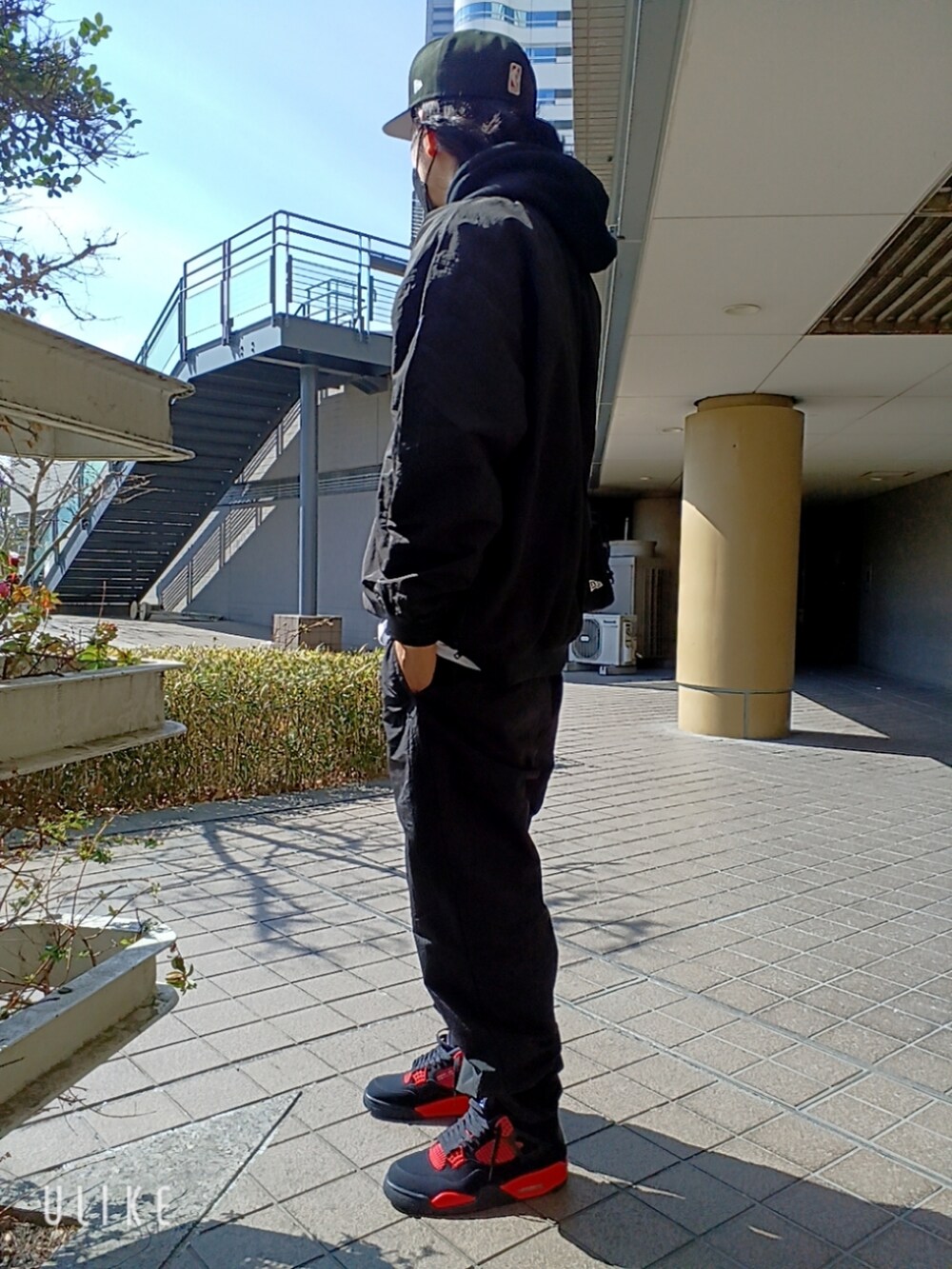 レッド系のスニーカー、ブラック系のカーゴパンツ、ブラック系のパーカーを着用したメンズの春コーディネートの3枚目の写真