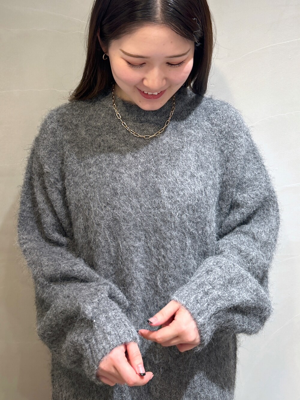 グレー系のニット/セーター、ブラック系のスカート、ホワイト系のショルダーバッグを着用したレディースの秋コーディネートの3枚目の写真