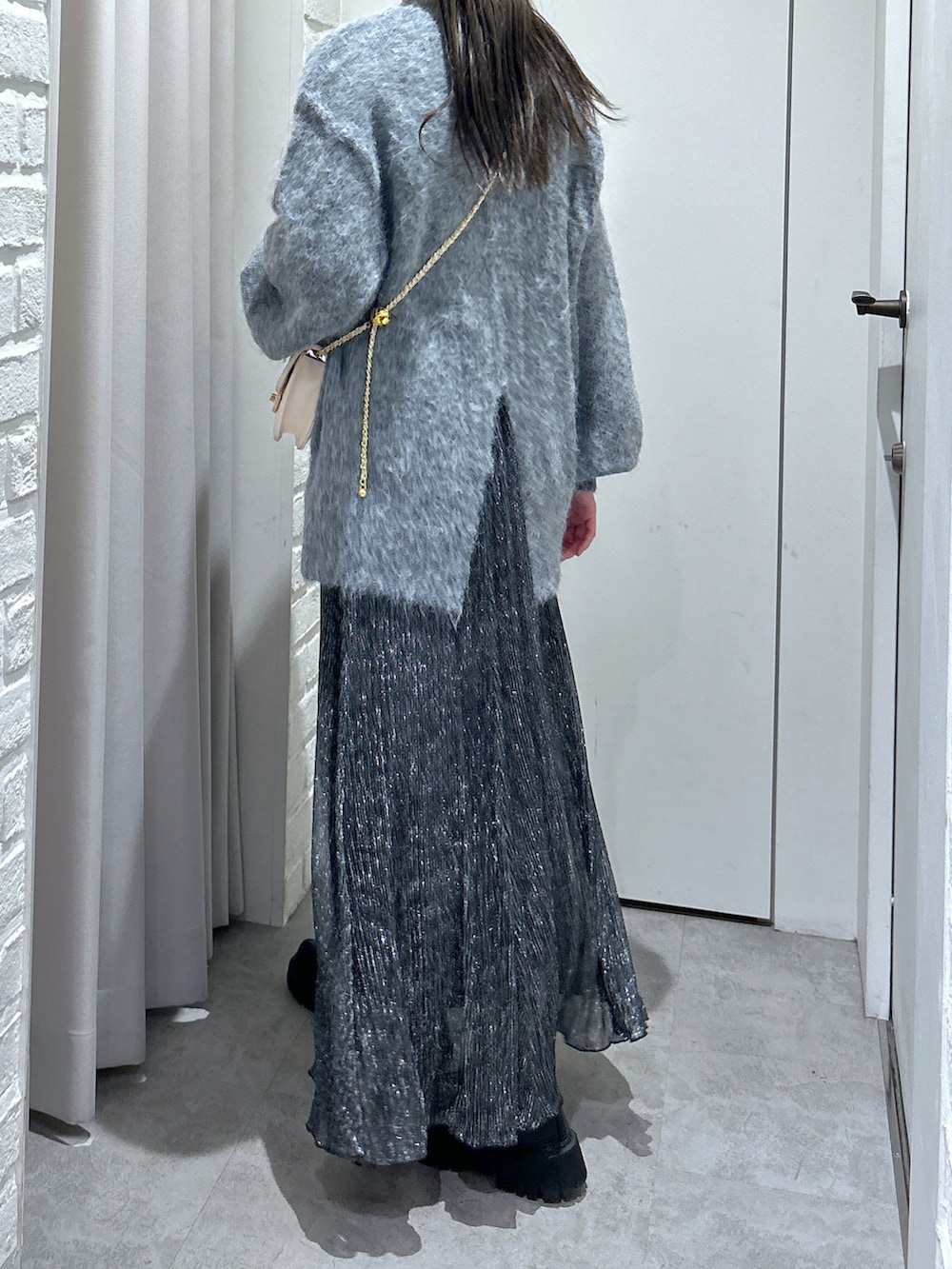 グレー系のニット/セーター、ブラック系のスカート、ホワイト系のショルダーバッグを着用したレディースの秋コーディネートの2枚目の写真