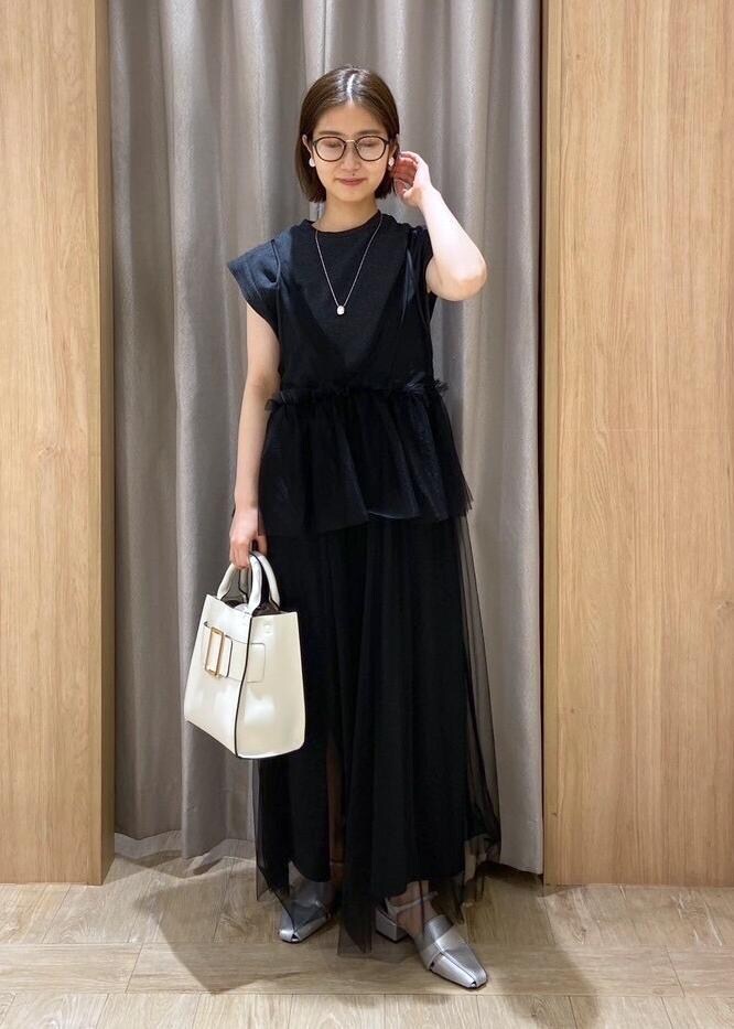 シルバー系のサンダル、ホワイト系のハンドバッグ、ブラック系のワンピースを着用したレディースの夏コーディネートの2枚目の写真