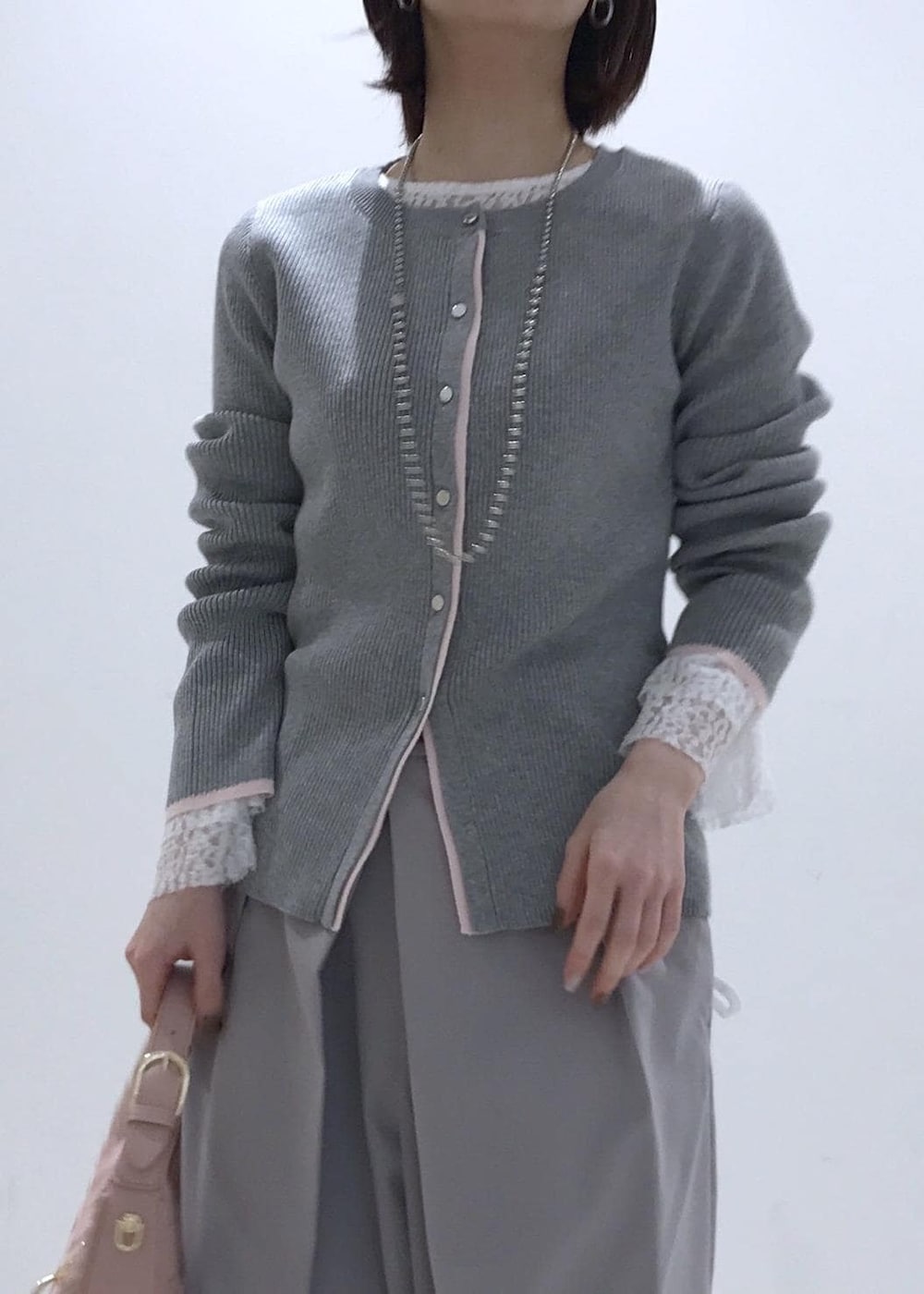 ピンク系のハンドバッグ、ベージュ系のパンプス、グレー系のカーディガン/ボレロを着用したレディースの冬コーディネートの4枚目の写真