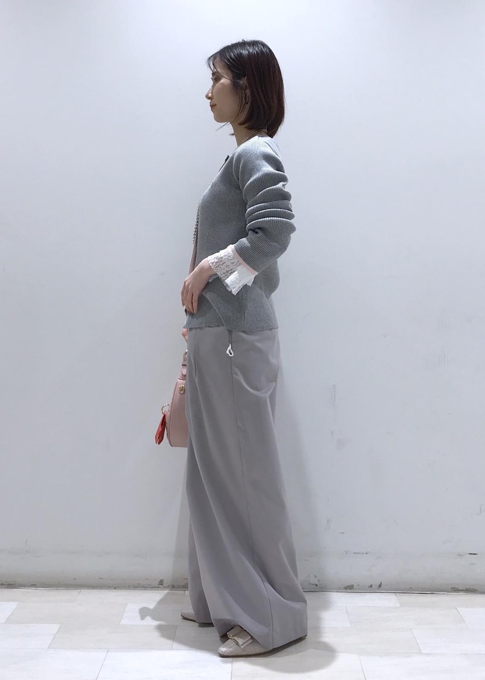 ピンク系のハンドバッグ、ベージュ系のパンプス、グレー系のカーディガン/ボレロを着用したレディースの冬コーディネートの3枚目の写真