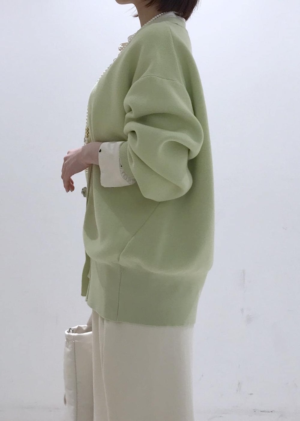 ホワイト系のパンプス、ホワイト系のシャツ/ブラウス、グリーン系のカーディガン/ボレロを着用したレディースの冬コーディネートの6枚目の写真