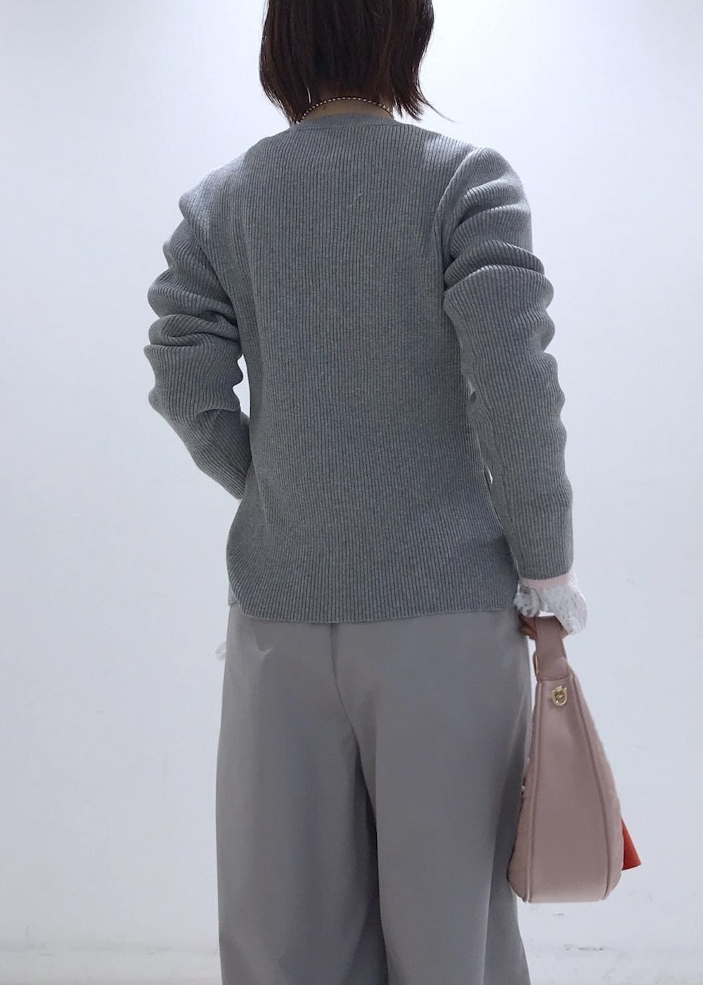 ピンク系のハンドバッグ、ベージュ系のパンプス、グレー系のカーディガン/ボレロを着用したレディースの冬コーディネートの6枚目の写真