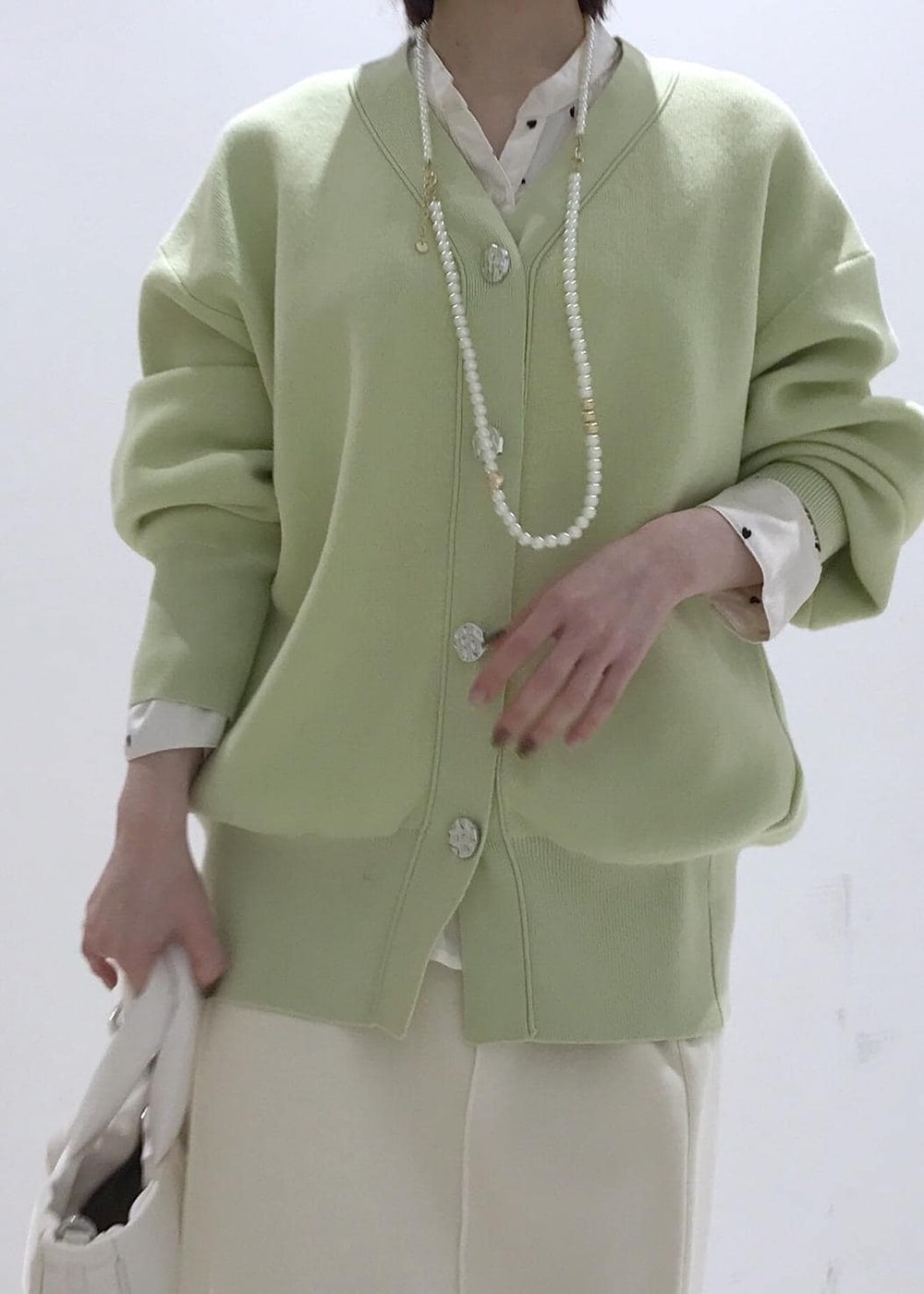 ホワイト系のパンプス、ホワイト系のシャツ/ブラウス、グリーン系のカーディガン/ボレロを着用したレディースの冬コーディネートの5枚目の写真