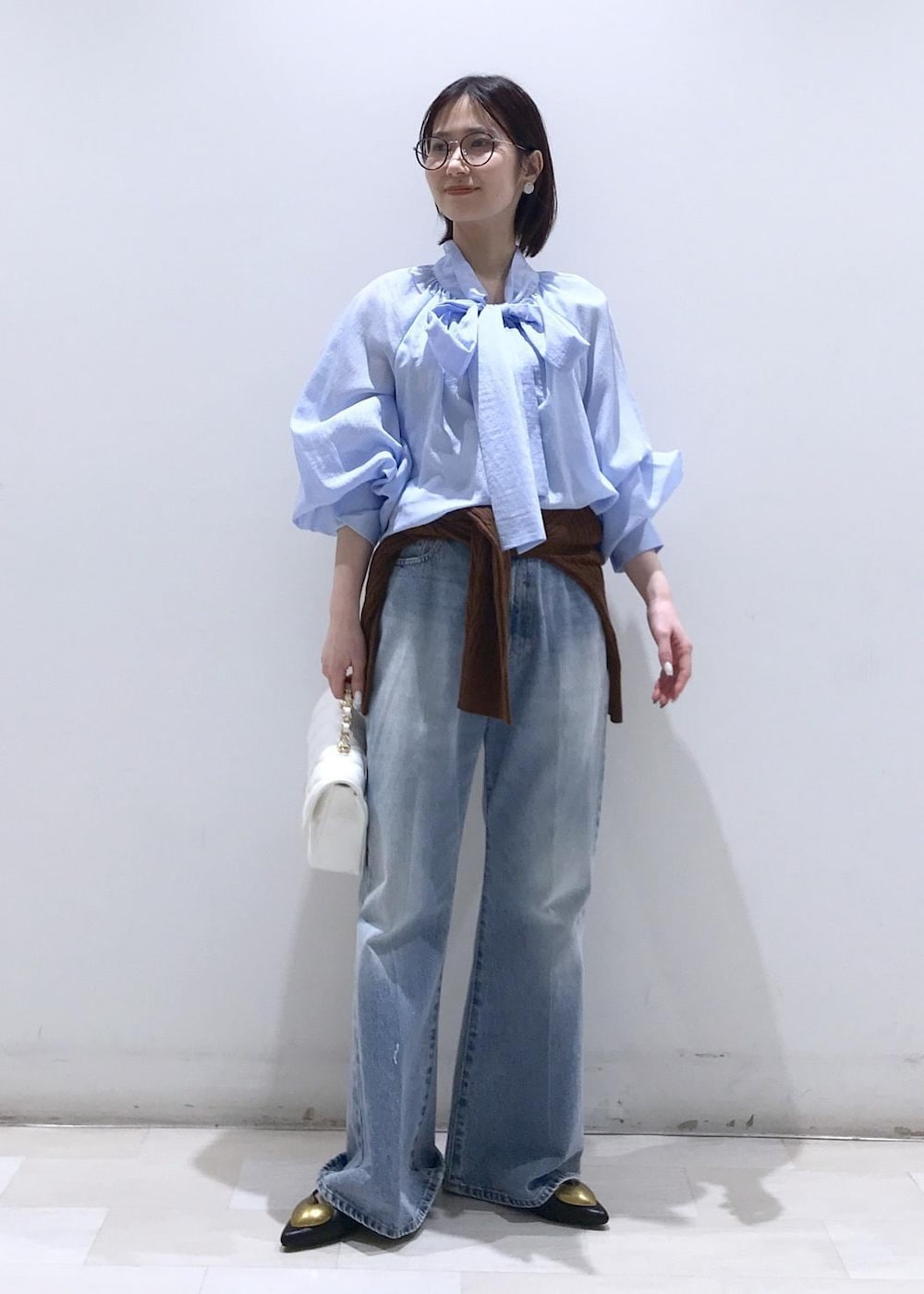 ブラック系のバレエシューズ、ブラウン系のカーディガン/ボレロ、ホワイト系のショルダーバッグを着用したレディースの冬コーディネートの2枚目の写真