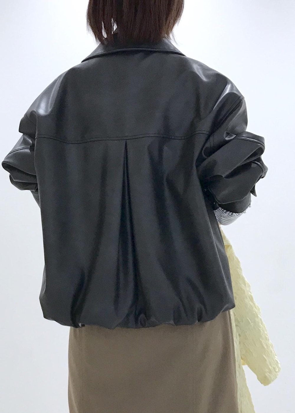 ホワイト系のショルダーバッグ、ブラック系のブルゾン、イエロー系のカーディガン/ボレロを着用したレディースの冬コーディネートの7枚目の写真