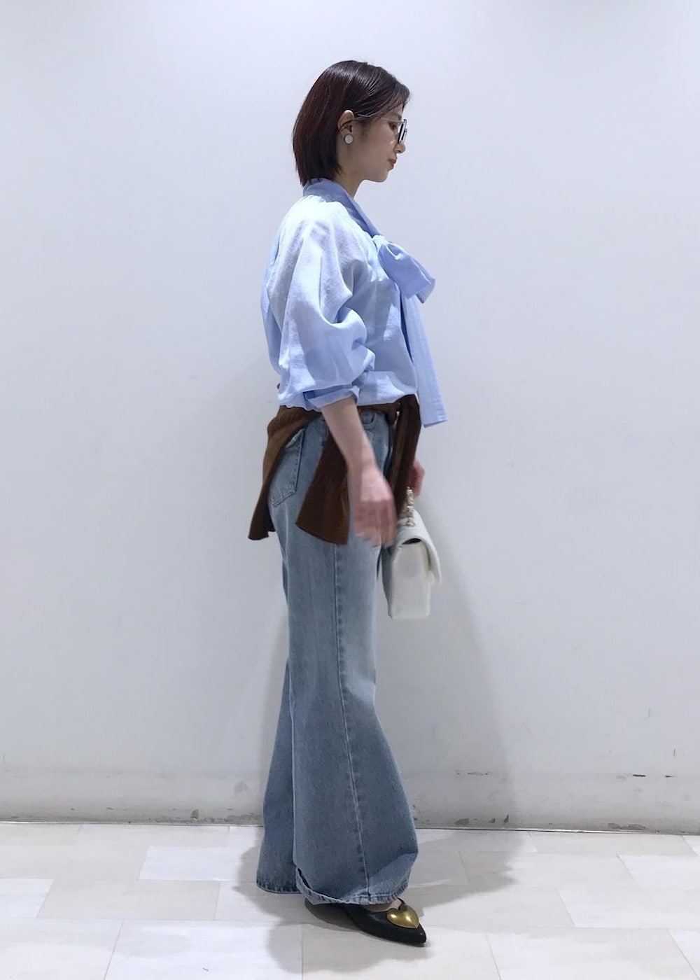 ブラック系のバレエシューズ、ブラウン系のカーディガン/ボレロ、ホワイト系のショルダーバッグを着用したレディースの冬コーディネートの3枚目の写真