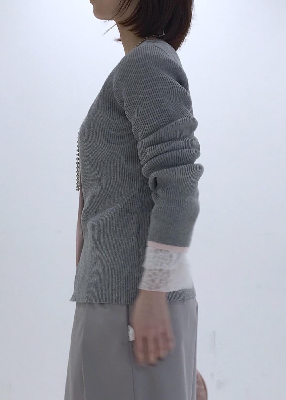 ピンク系のハンドバッグ、ベージュ系のパンプス、グレー系のカーディガン/ボレロを着用したレディースの冬コーディネートの5枚目の写真