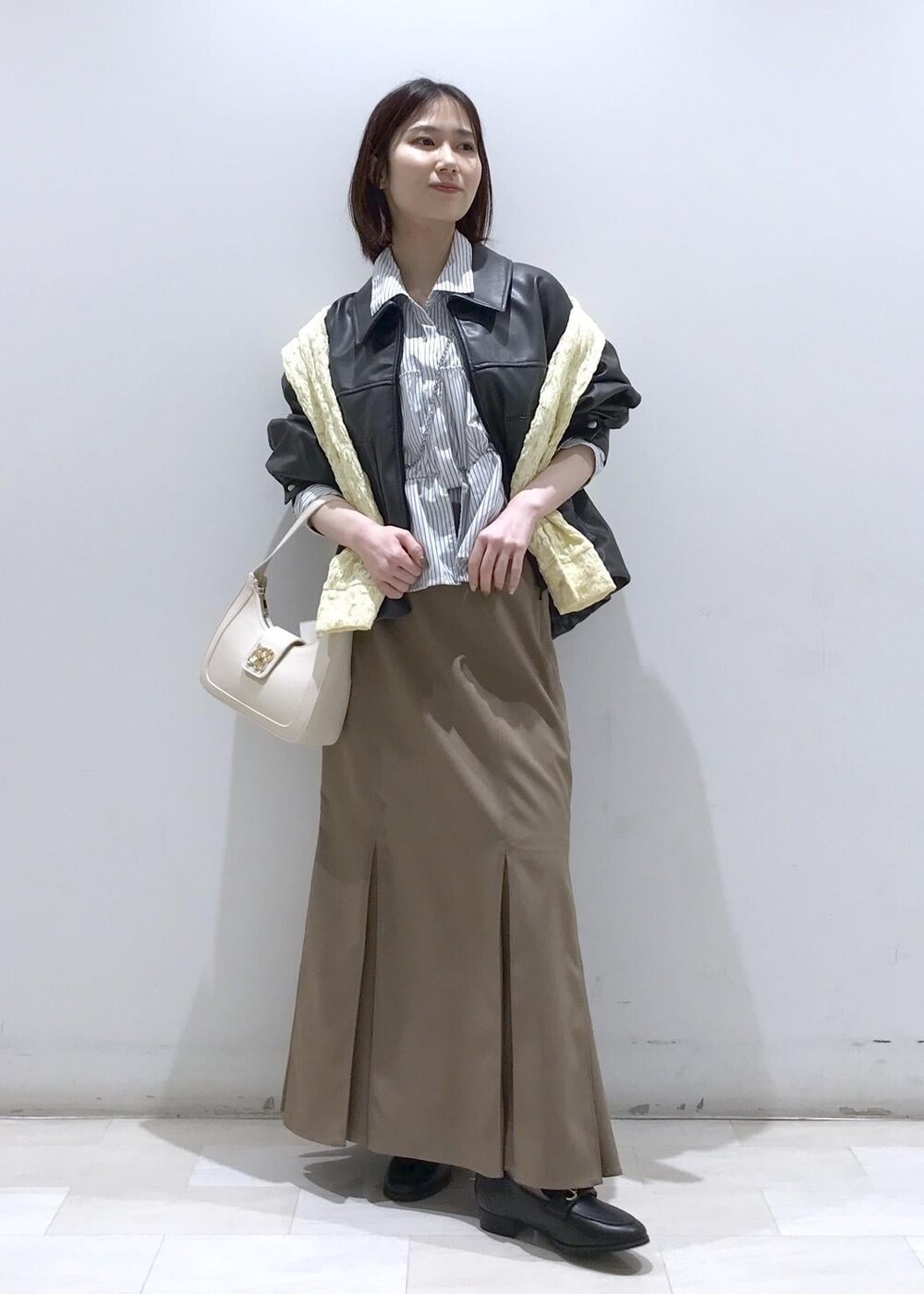 ホワイト系のショルダーバッグ、ブラック系のブルゾン、イエロー系のカーディガン/ボレロを着用したレディースの冬コーディネートの2枚目の写真