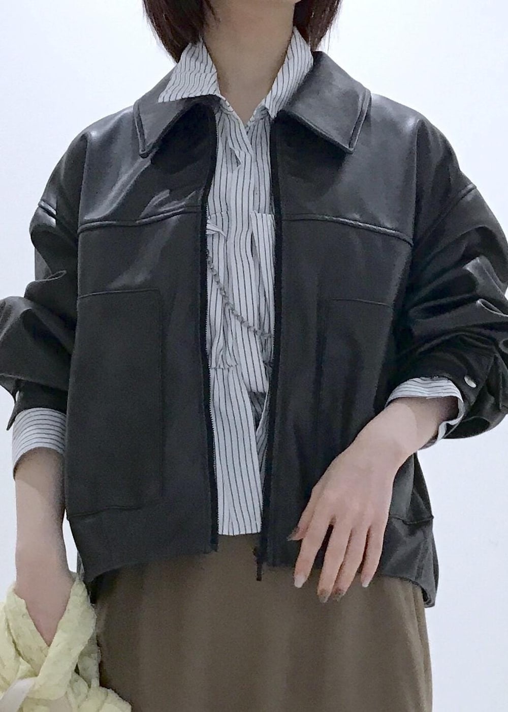 ホワイト系のショルダーバッグ、ブラック系のブルゾン、イエロー系のカーディガン/ボレロを着用したレディースの冬コーディネートの6枚目の写真