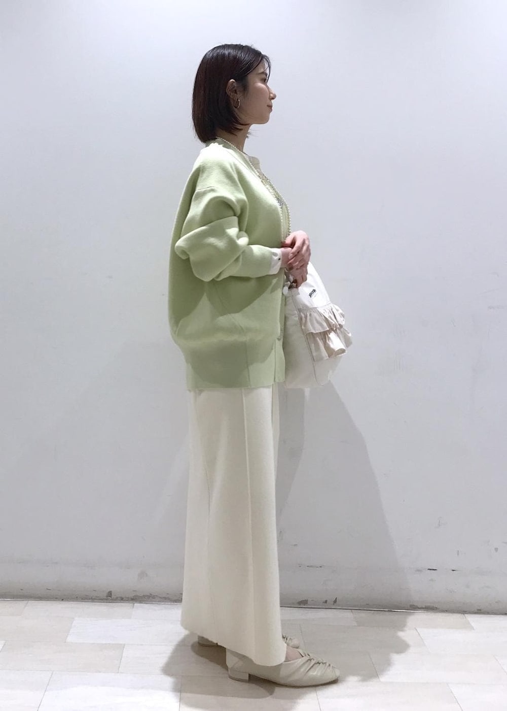 ホワイト系のパンプス、ホワイト系のシャツ/ブラウス、グリーン系のカーディガン/ボレロを着用したレディースの冬コーディネートの3枚目の写真