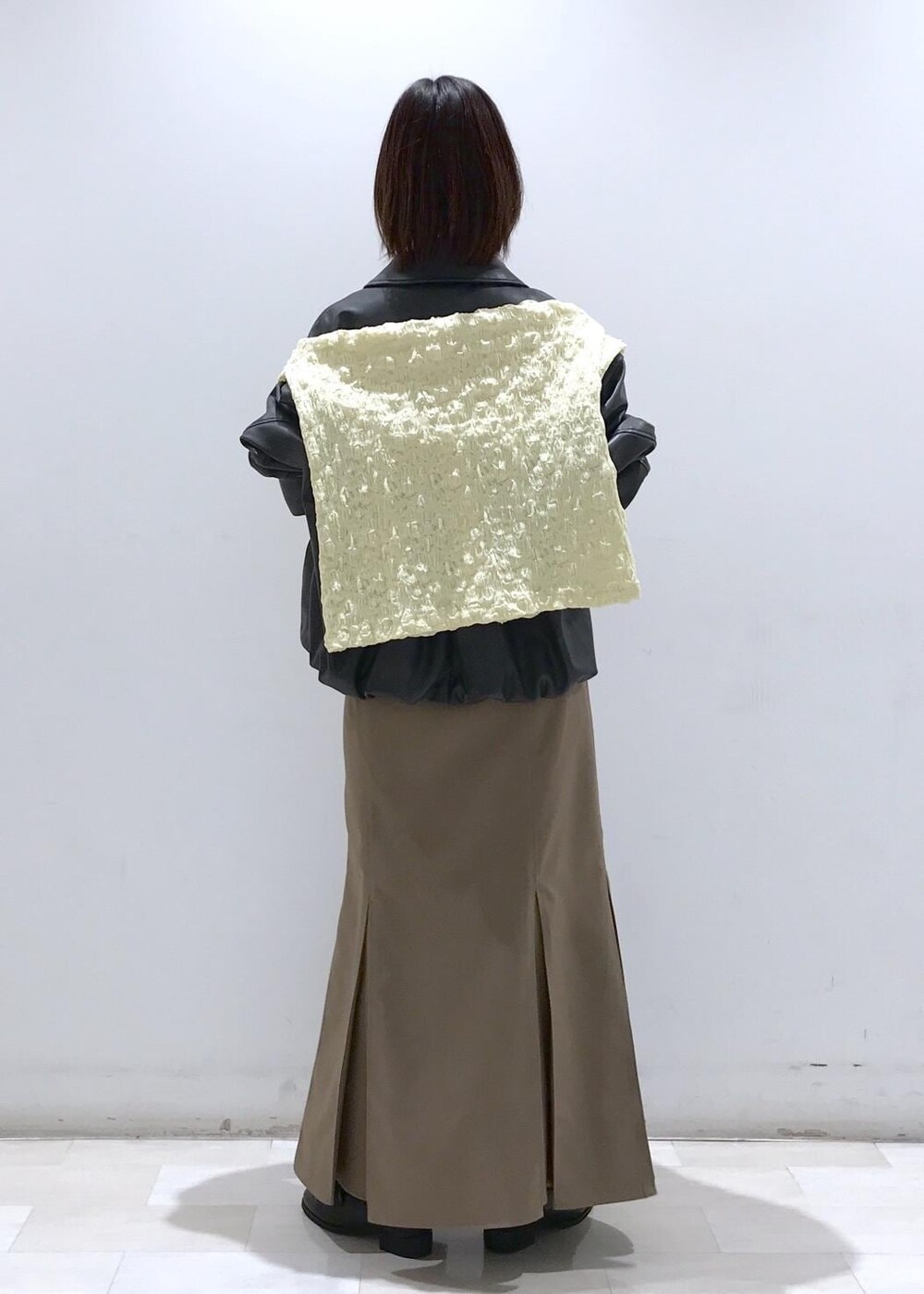 ホワイト系のショルダーバッグ、ブラック系のブルゾン、イエロー系のカーディガン/ボレロを着用したレディースの冬コーディネートの4枚目の写真