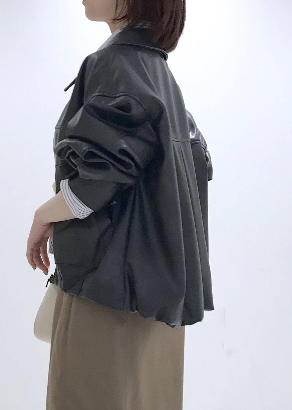 ホワイト系のショルダーバッグ、ブラック系のブルゾン、イエロー系のカーディガン/ボレロを着用したレディースの冬コーディネートの8枚目の写真