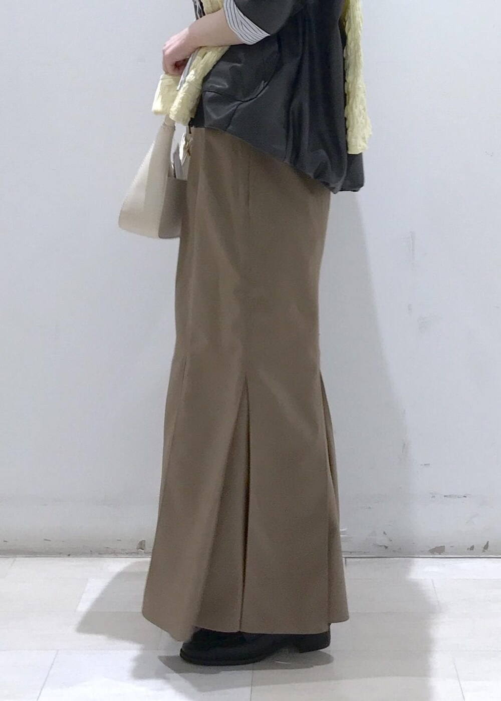 ホワイト系のショルダーバッグ、ブラック系のブルゾン、イエロー系のカーディガン/ボレロを着用したレディースの冬コーディネートの10枚目の写真