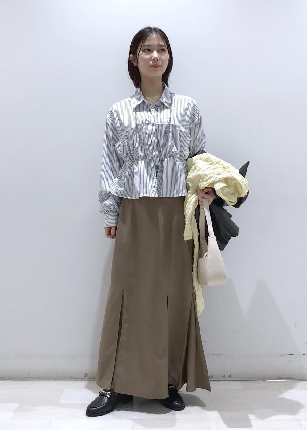 ホワイト系のショルダーバッグ、ブラック系のブルゾン、イエロー系のカーディガン/ボレロを着用したレディースの冬コーディネートの5枚目の写真