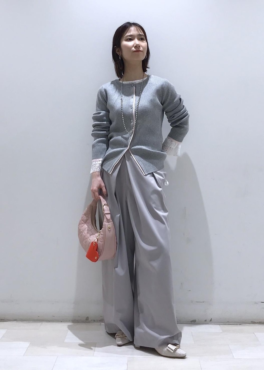 ピンク系のハンドバッグ、ベージュ系のパンプス、グレー系のカーディガン/ボレロを着用したレディースの冬コーディネートの2枚目の写真