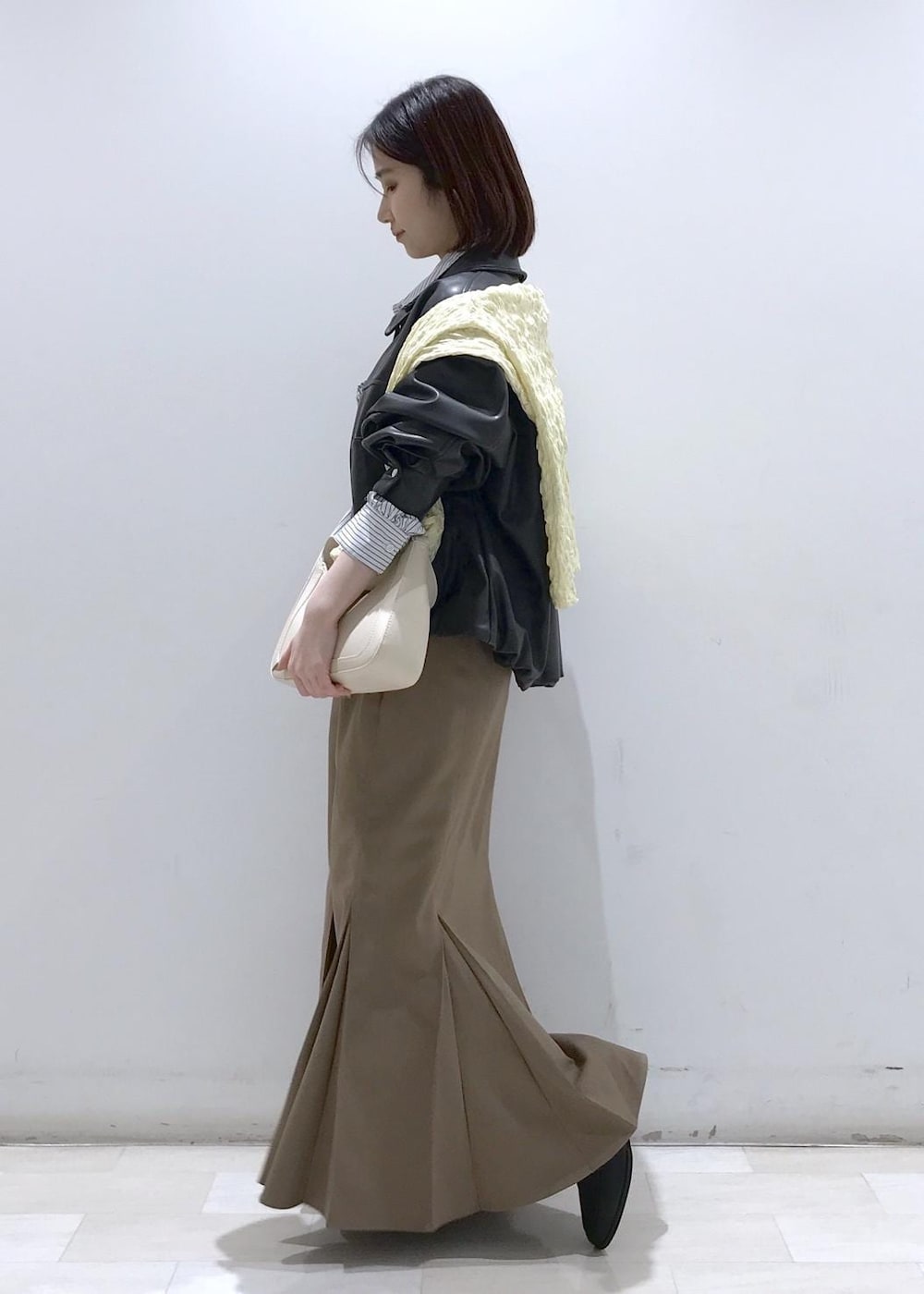 ホワイト系のショルダーバッグ、ブラック系のブルゾン、イエロー系のカーディガン/ボレロを着用したレディースの冬コーディネートの3枚目の写真