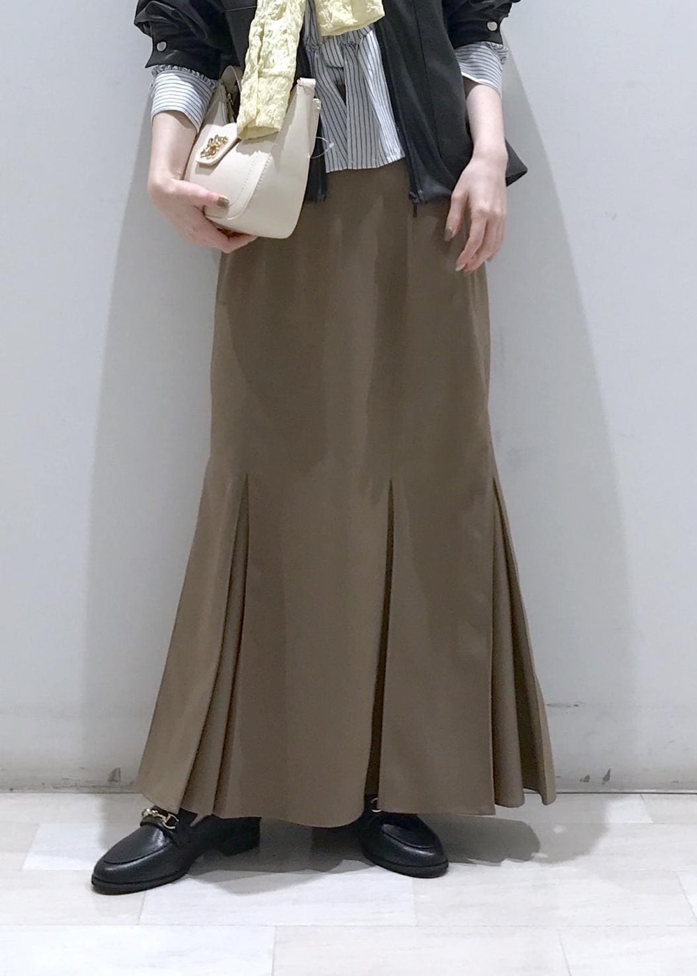 ホワイト系のショルダーバッグ、ブラック系のブルゾン、イエロー系のカーディガン/ボレロを着用したレディースの冬コーディネートの9枚目の写真