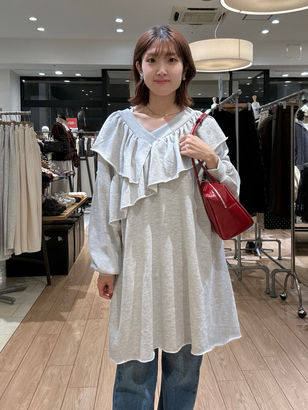 グレー系のワンピース、ブルー系のデニムパンツ、ブラック系のローファーを着用したレディースの秋コーディネートの2枚目の写真