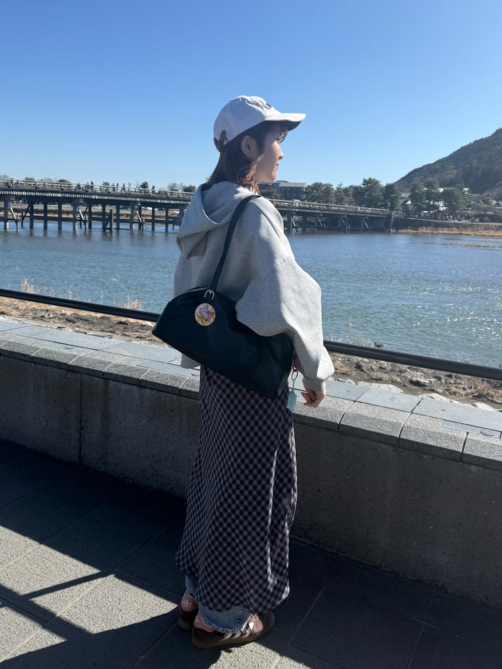 グレー系のパーカー、グレー系のスカート、ブラック系のボストンバッグを着用したレディースの冬コーディネートの2枚目の写真