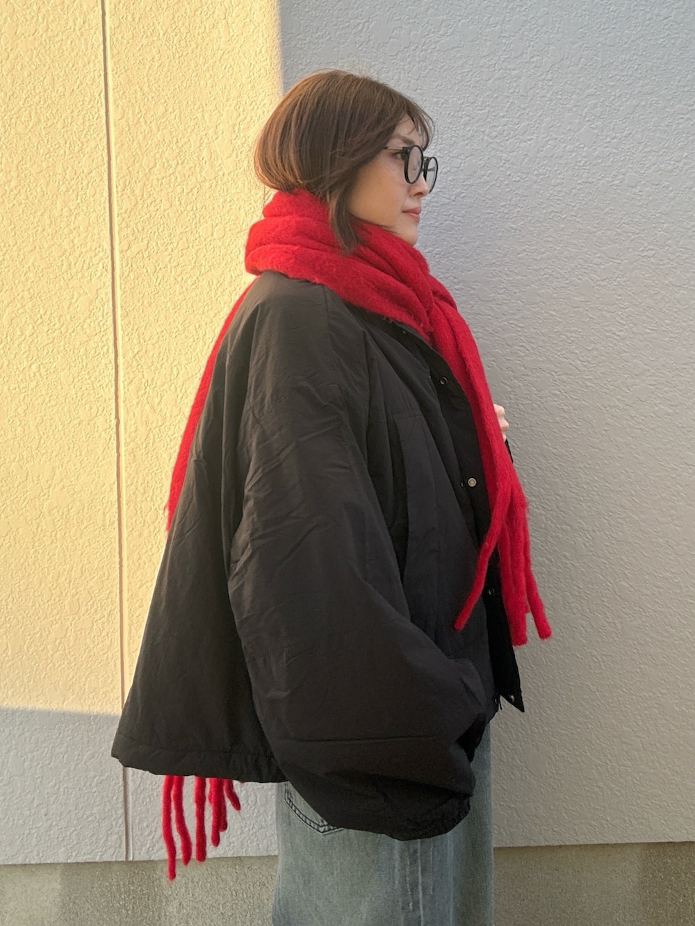 ブラック系のその他アウター、レッド系のマフラー、その他のサングラスを着用したレディースの冬コーディネートの2枚目の写真