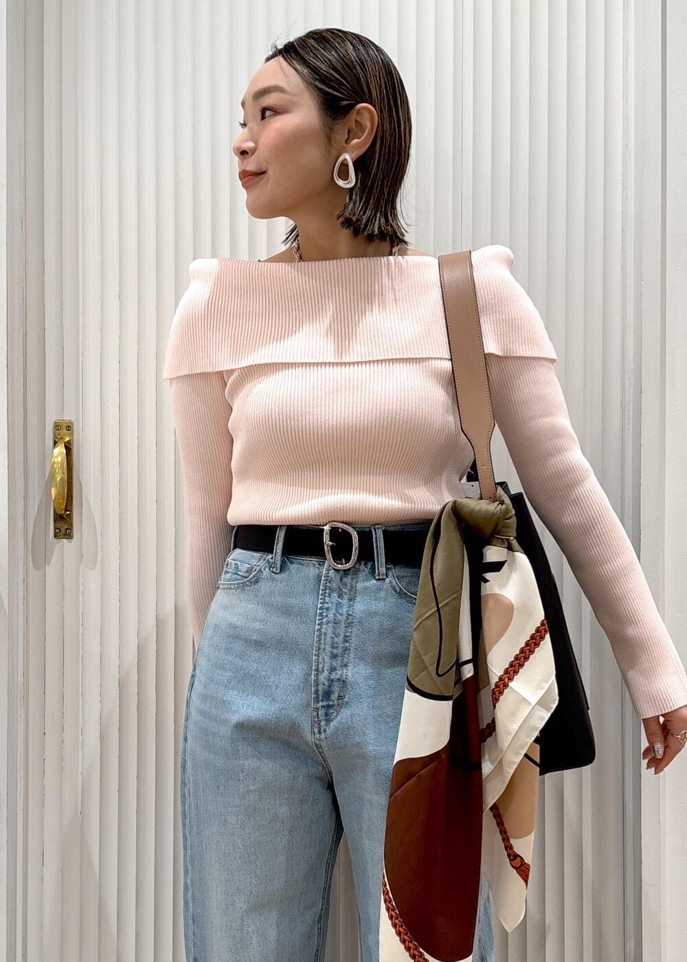 ブルー系のデニムパンツ、ブラック系のトートバッグ、ピンク系のニット/セーターを着用したレディースの春コーディネートの9枚目の写真