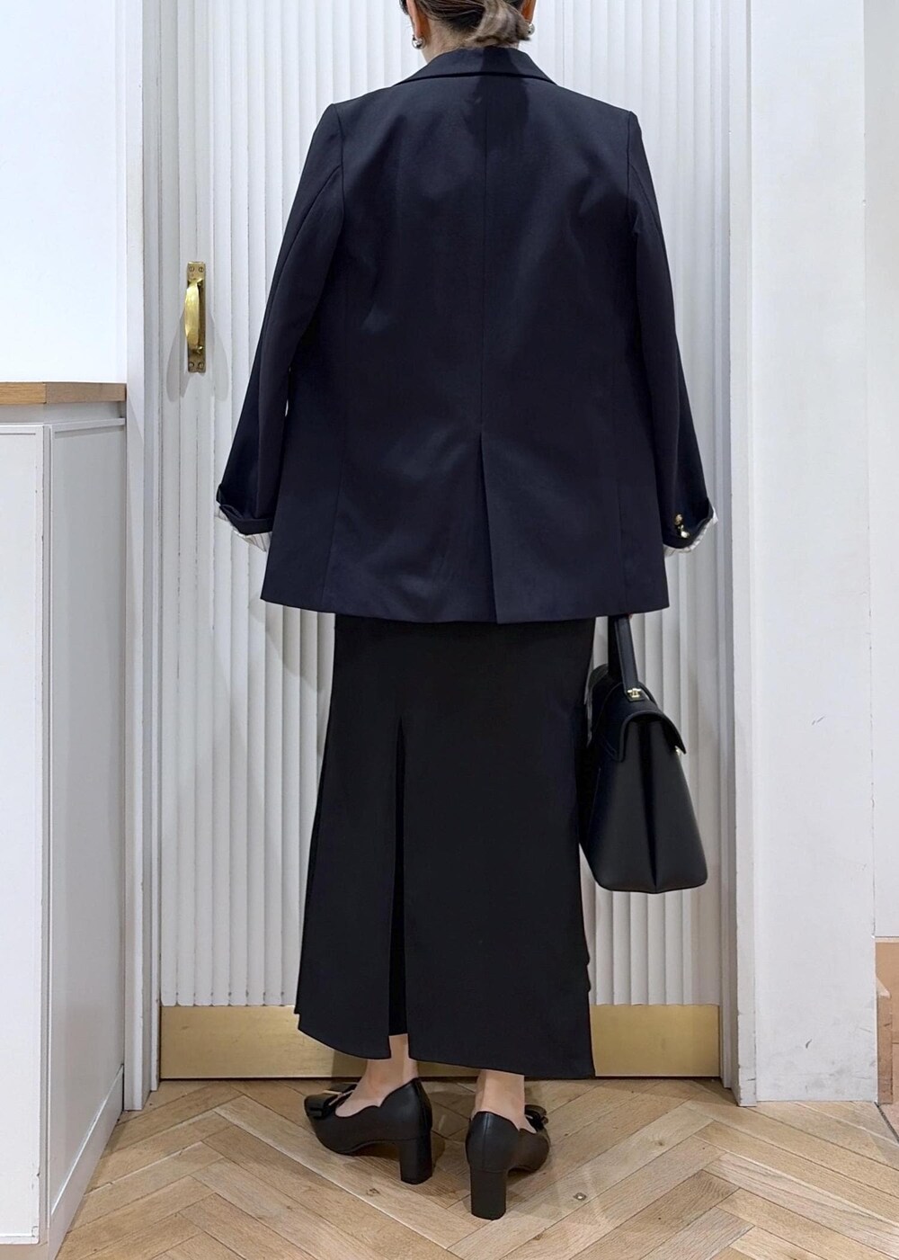 ブラック系のハンドバッグ、ホワイト系のニット/セーター、ブラック系のパンプスを着用したレディースの冬コーディネートの3枚目の写真