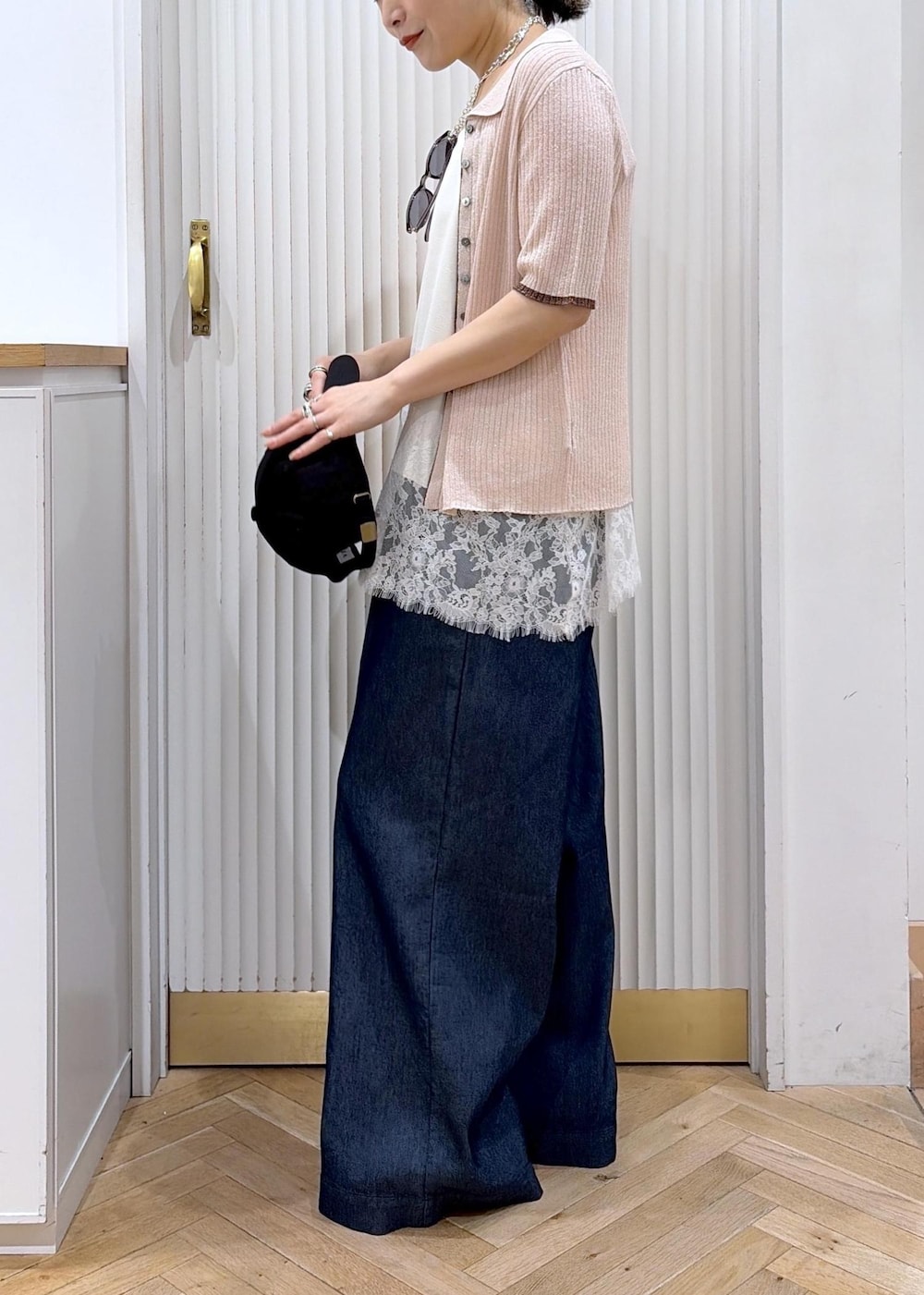ブルー系のデニムパンツ、ホワイト系のキャミソール、ピンク系のカーディガン/ボレロを着用したレディースの春コーディネートの3枚目の写真