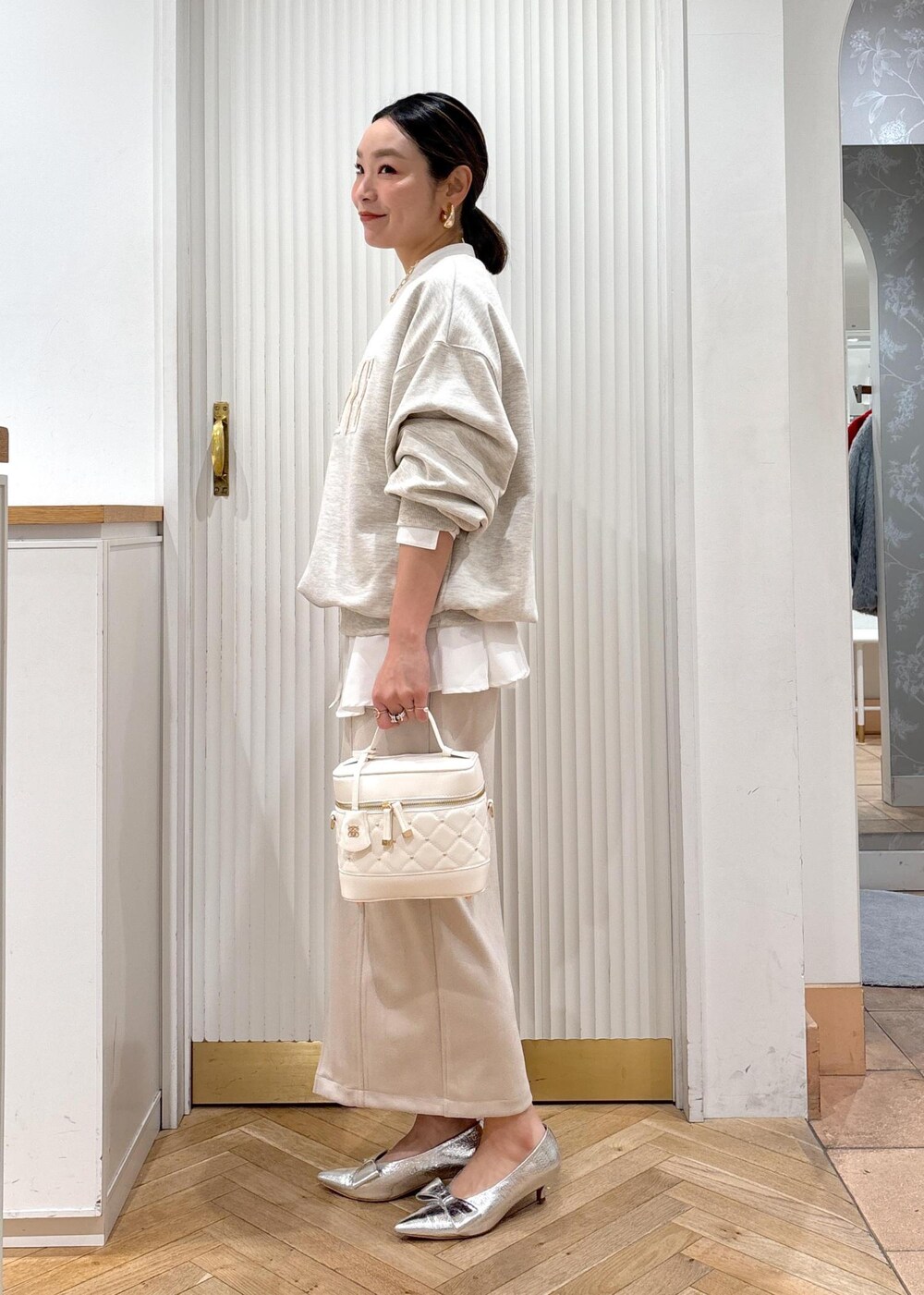 シルバー系のパンプス、ホワイト系のスウェット、ホワイト系のシャツ/ブラウスを着用したレディースの冬コーディネートの2枚目の写真