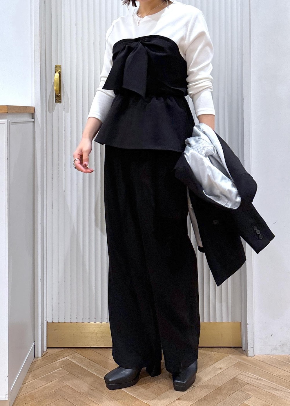 ブラック系のスラックス、ブラック系のテーラードジャケット、ブラック系のブーツを着用したレディースの秋コーディネートの2枚目の写真