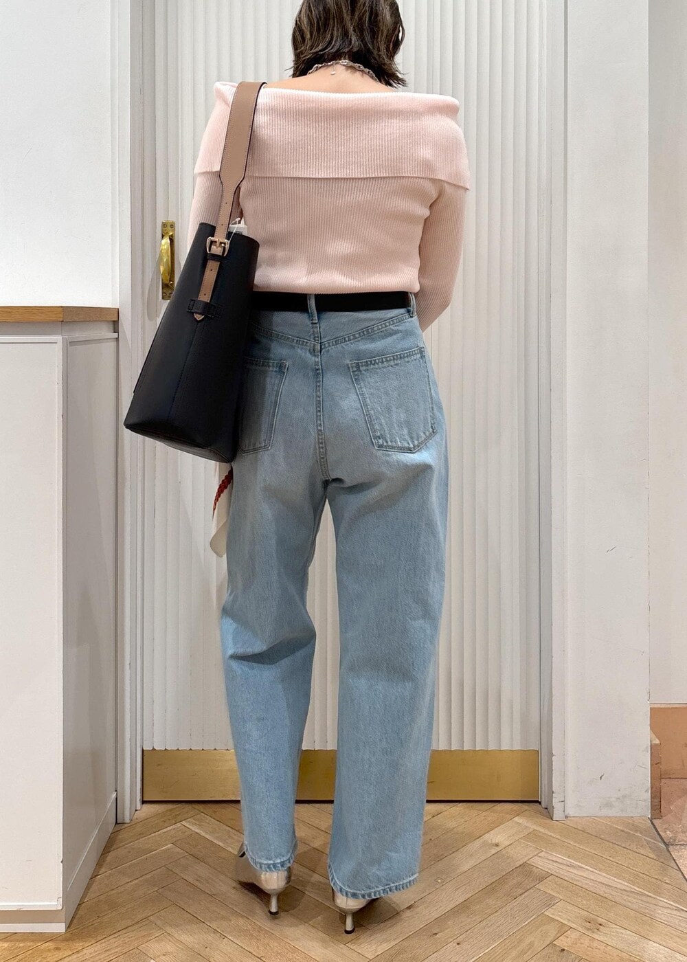ブルー系のデニムパンツ、ブラック系のトートバッグ、ピンク系のニット/セーターを着用したレディースの春コーディネートの4枚目の写真