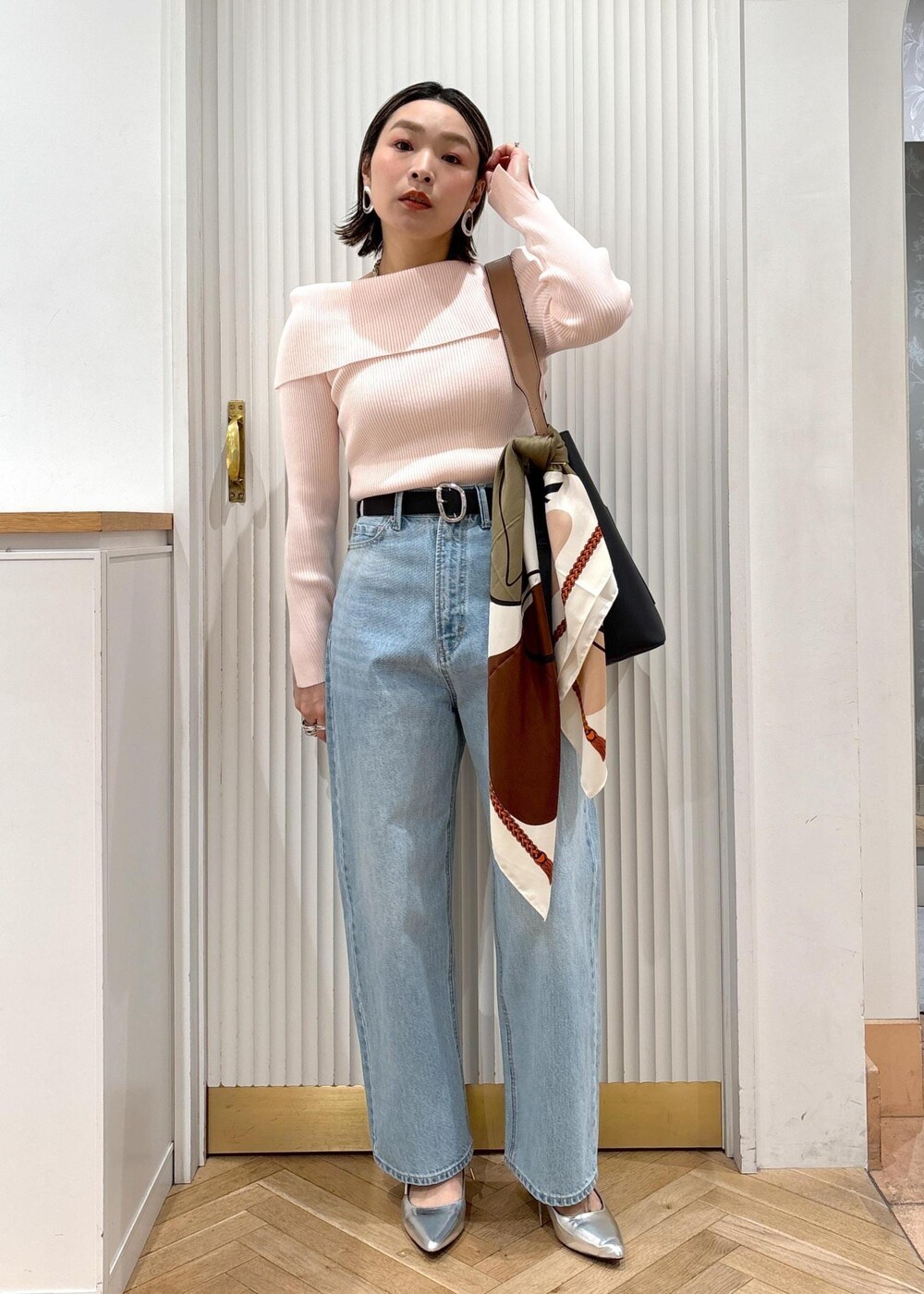 ブルー系のデニムパンツ、ブラック系のトートバッグ、ピンク系のニット/セーターを着用したレディースの春コーディネートの2枚目の写真