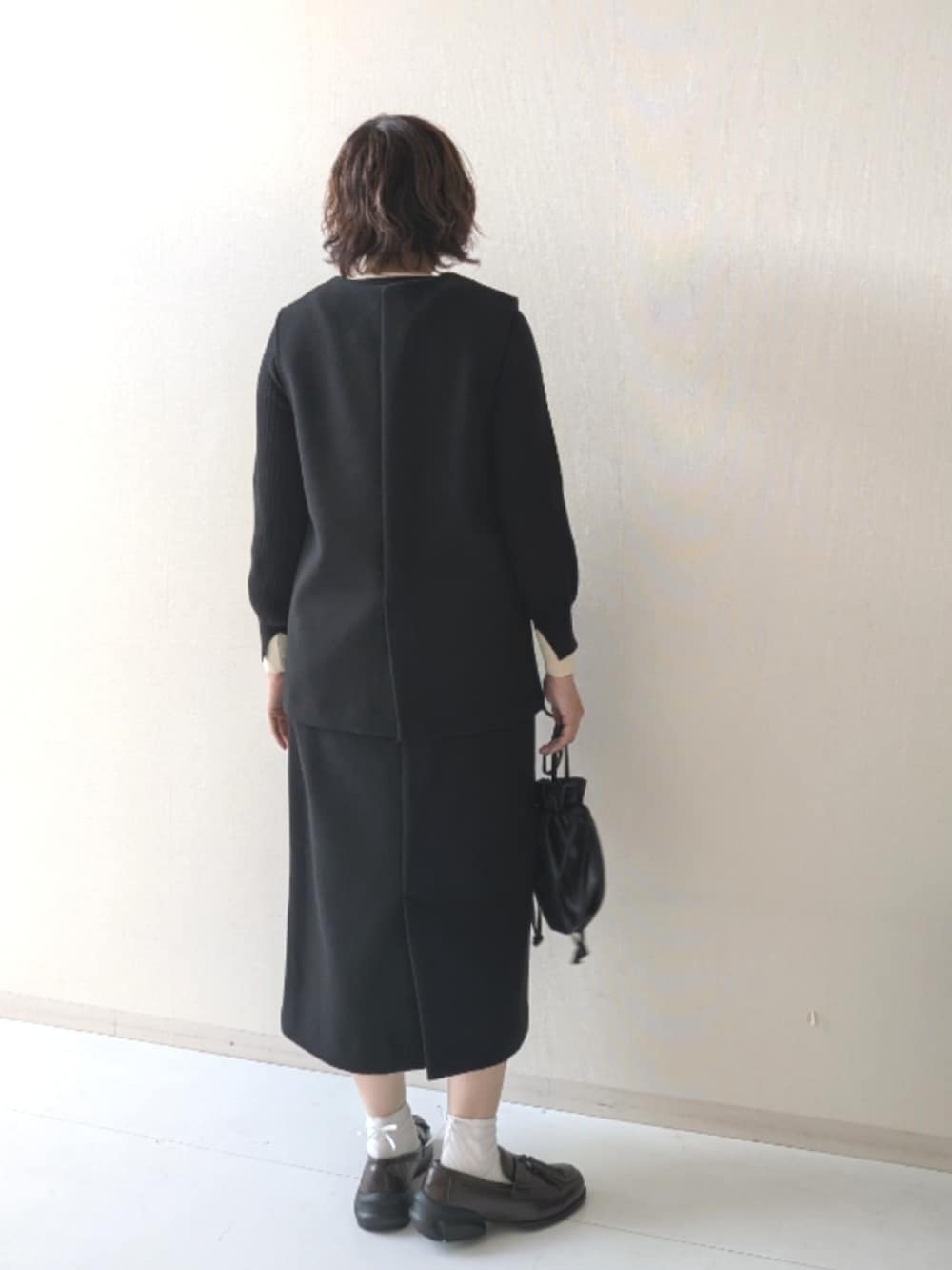 ブラウン系のスニーカー、ブラック系のニット/セーター、ブラック系のベストを着用したレディースの秋コーディネートの3枚目の写真