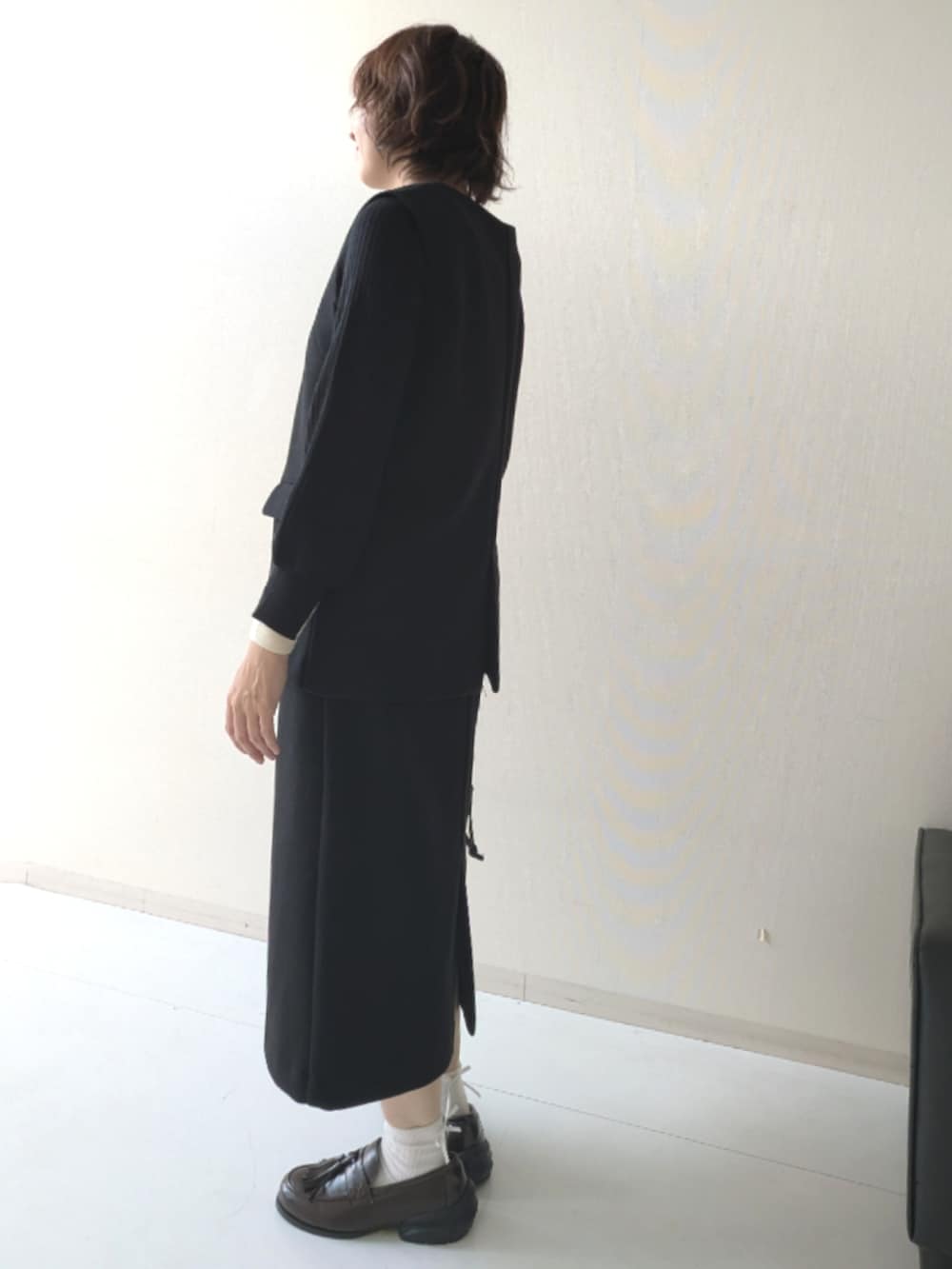 ブラウン系のスニーカー、ブラック系のニット/セーター、ブラック系のベストを着用したレディースの秋コーディネートの2枚目の写真