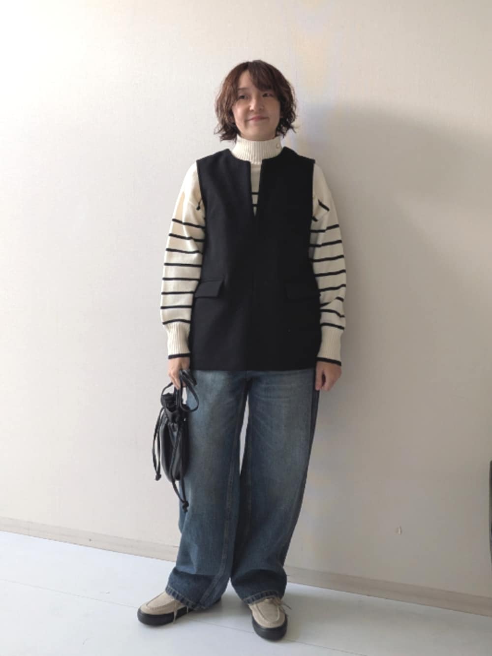 ブラウン系のスニーカー、ブラック系のニット/セーター、ブラック系のベストを着用したレディースの秋コーディネートの9枚目の写真