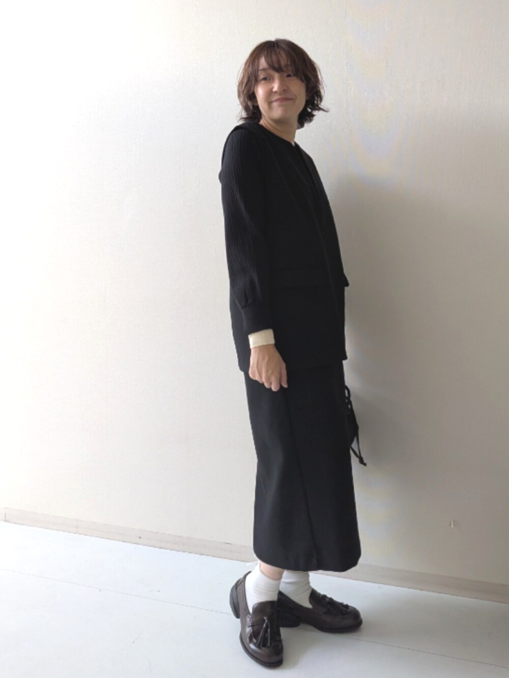 ブラウン系のスニーカー、ブラック系のニット/セーター、ブラック系のベストを着用したレディースの秋コーディネートの4枚目の写真