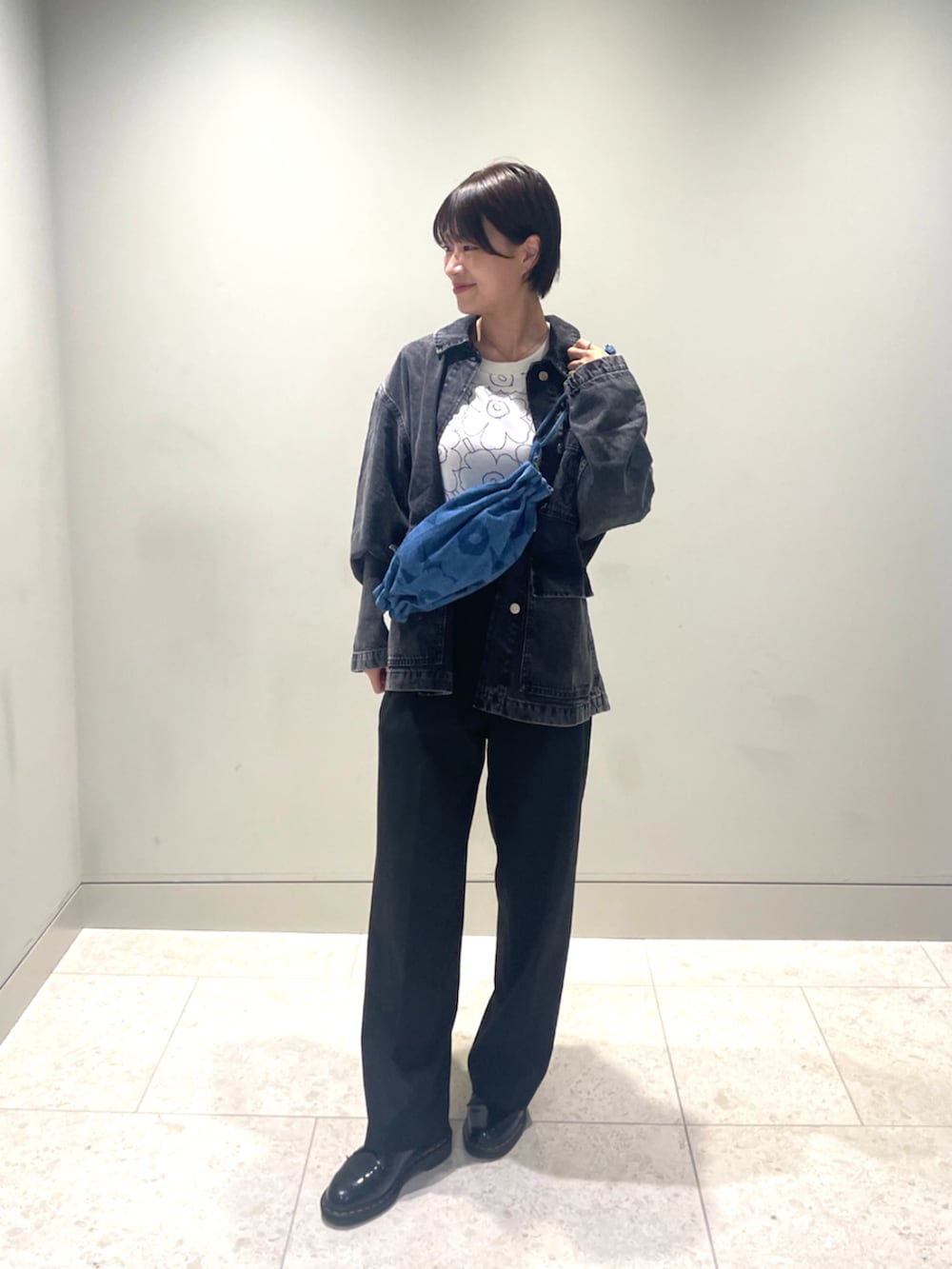 ブルー系のショルダーバッグ、ブラック系のデニムジャケット、ホワイト系のTシャツ/カットソーを着用したレディースの秋コーディネートの2枚目の写真