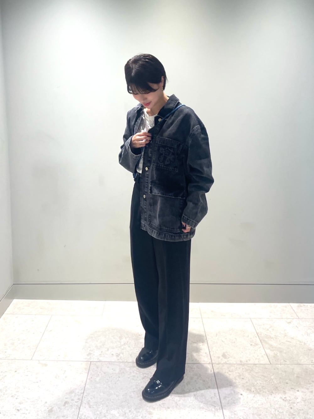 ブルー系のショルダーバッグ、ブラック系のデニムジャケット、ホワイト系のTシャツ/カットソーを着用したレディースの秋コーディネートの3枚目の写真