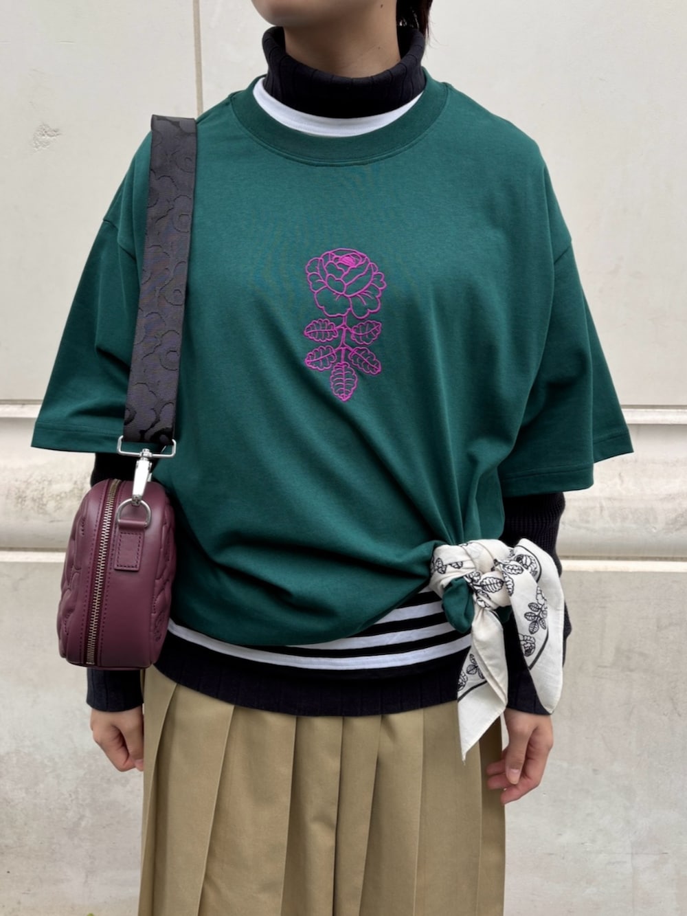 レッド系のショルダーバッグ、グリーン系のTシャツ/カットソー、ホワイト系のストール/ショールを着用したレディースの冬コーディネートの4枚目の写真