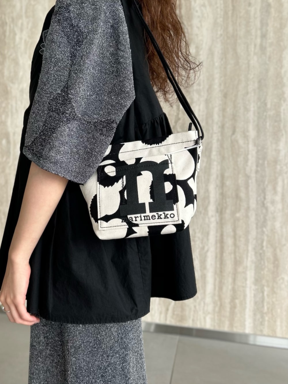 ブラック系のニット/セーター、ブラック系のスカート、ブラック系のショルダーバッグを着用したレディースの夏コーディネートの4枚目の写真