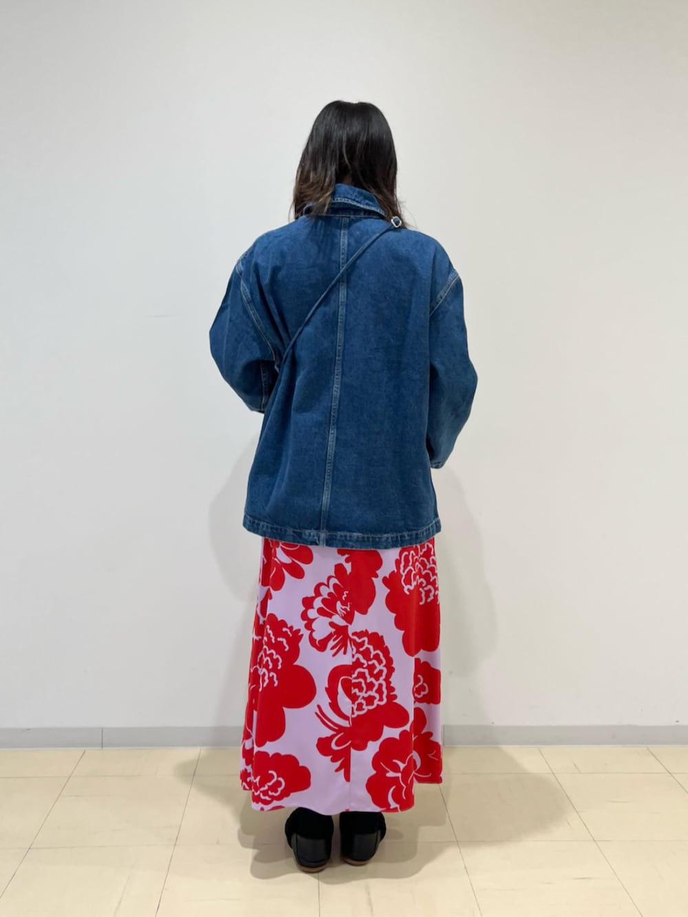パープル系のスカート、ブルー系のデニムジャケット、ブルー系のショルダーバッグを着用したレディースの夏コーディネートの2枚目の写真