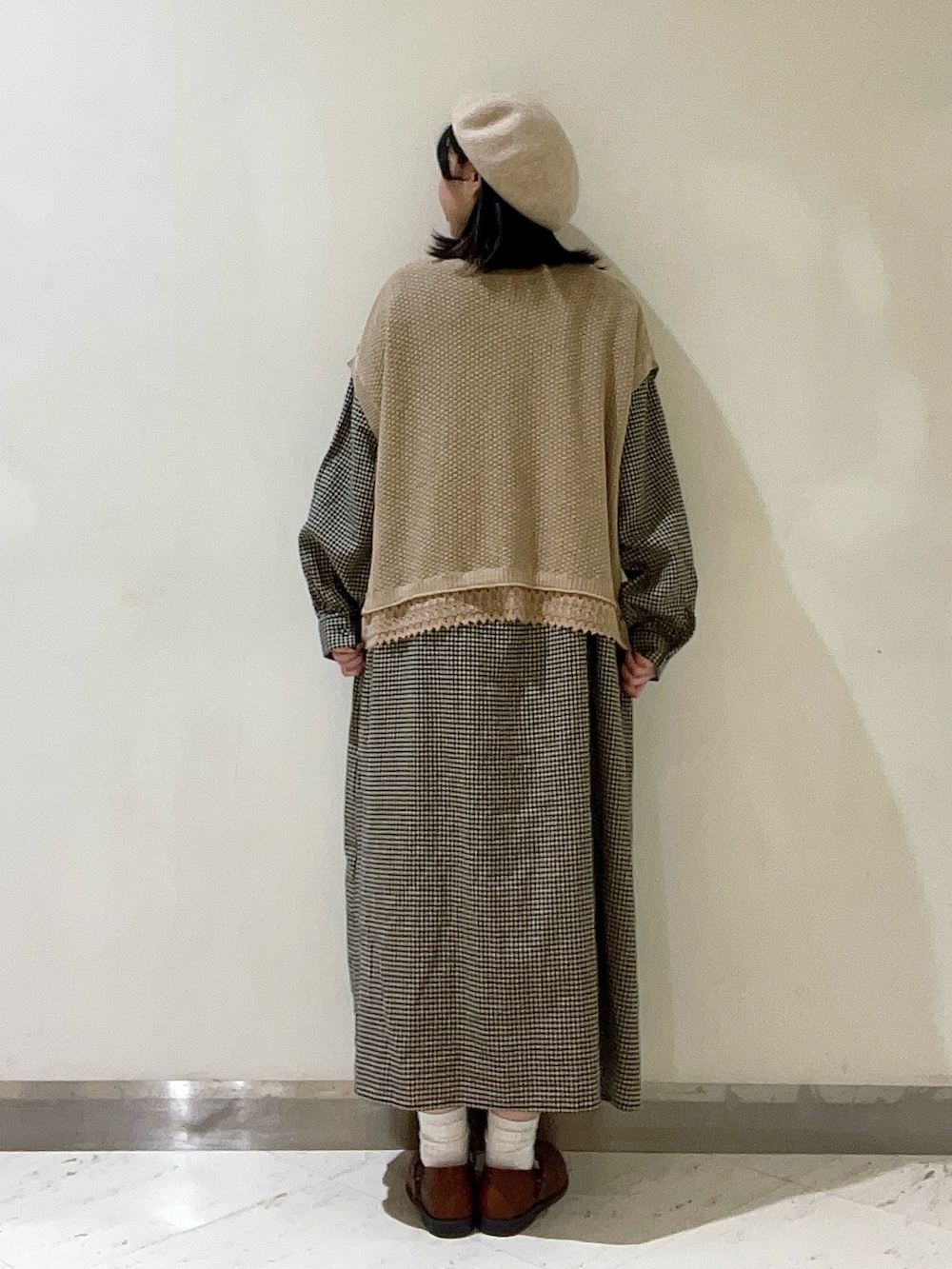 ベージュ系のベスト、イエロー系のドレスシューズ、ベージュ系のワンピースを着用したレディースの冬コーディネートの2枚目の写真