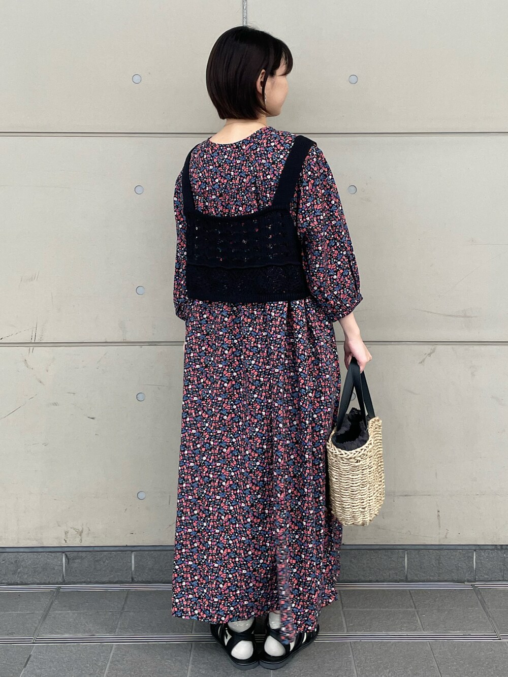 ブラック系のサンダル、ブラック系のハンドバッグ、ブラック系のベストを着用したレディースの夏コーディネートの2枚目の写真