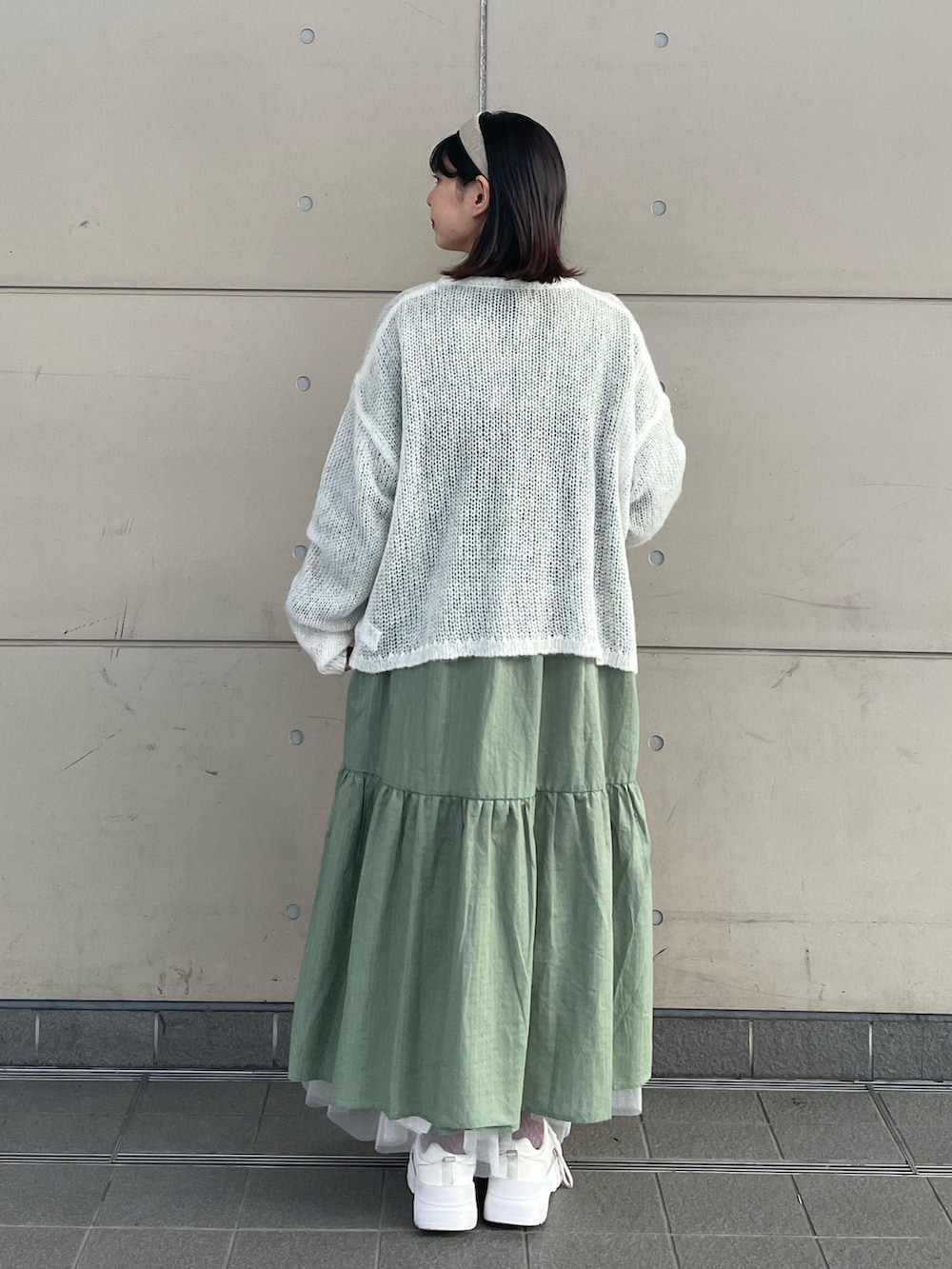 ベージュ系のハンドバッグ、グリーン系のワンピース、ホワイト系のカーディガン/ボレロを着用したレディースの冬コーディネートの2枚目の写真