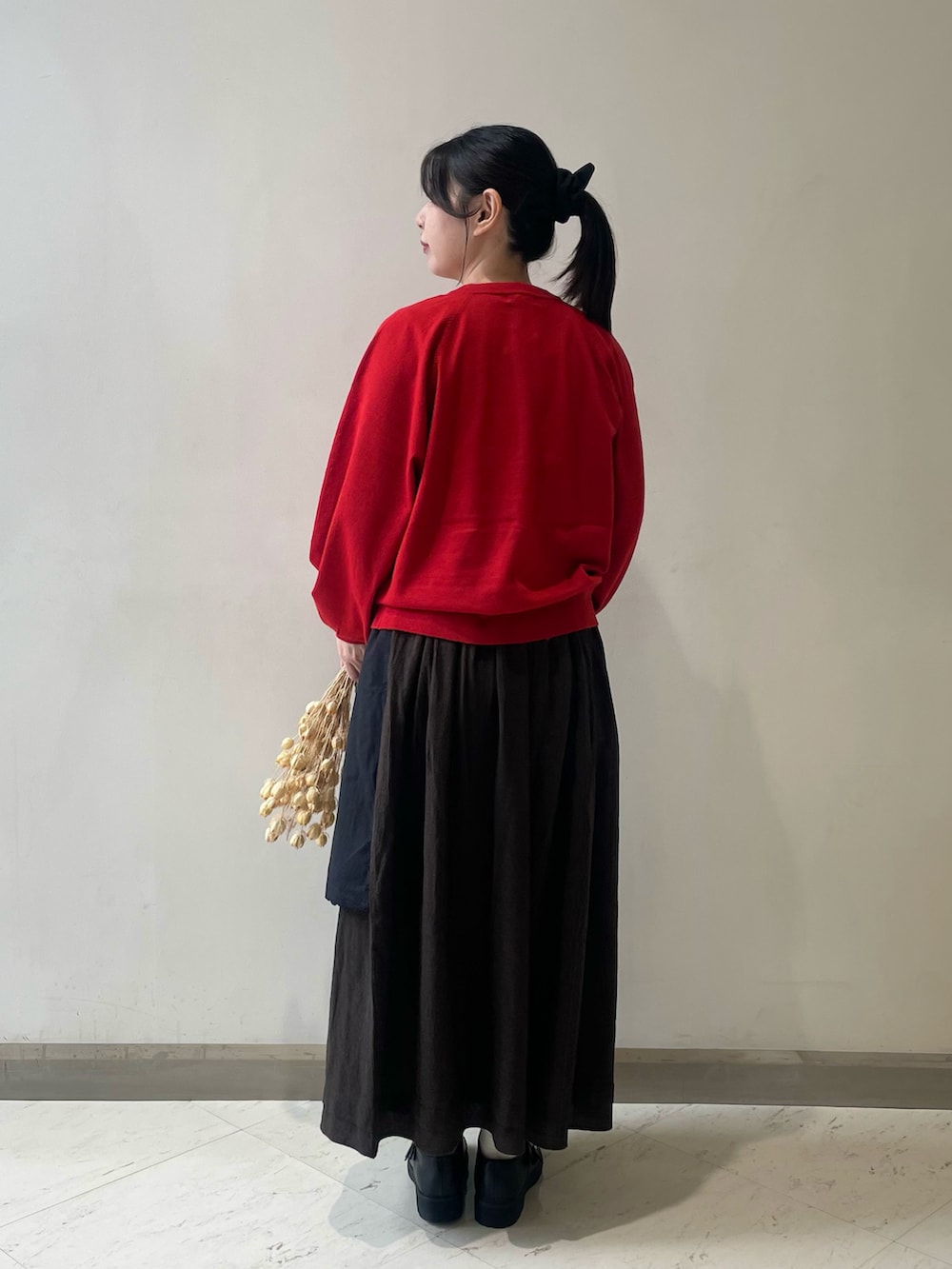 レッド系のカーディガン/ボレロ、ブラック系のスカート、ブラック系のドレスシューズを着用したレディースの冬コーディネートの2枚目の写真